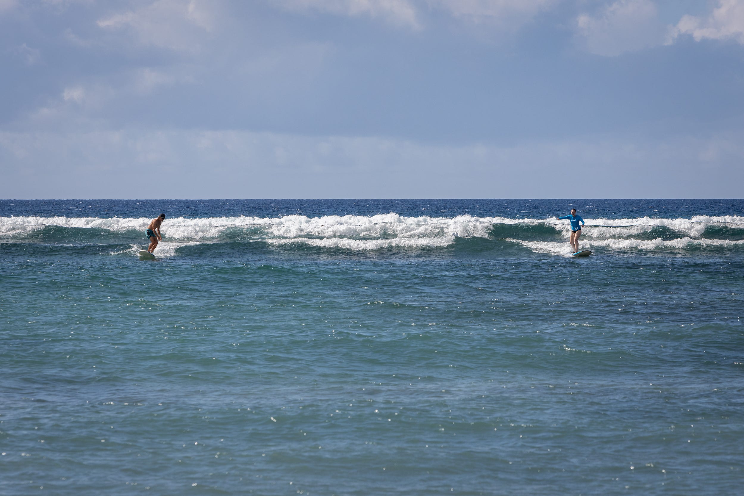 Two people surfing in the ocean.