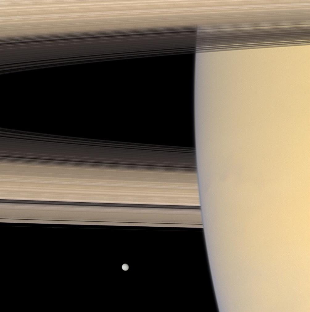 saturn rings up close with distant moon mimas in the background