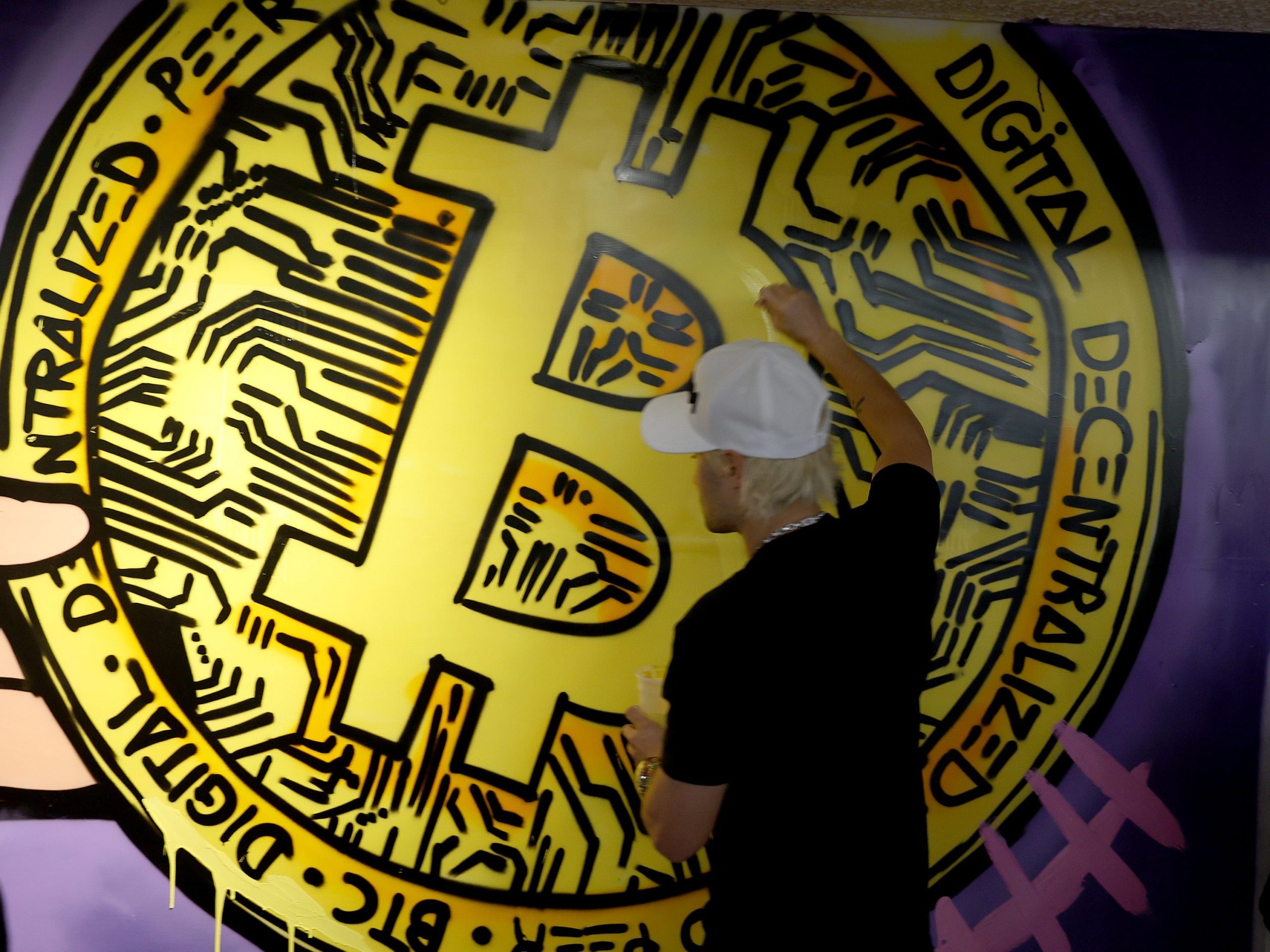 A person paints a bitcoin onto a mural at the North American Bitcoin Conference held at the James L Knight Center on January 18, 2022 in Miami, Florida.