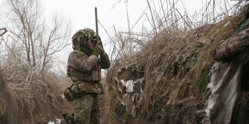 A Ukrainian Military Forces serviceman, watches through spyglass in a trench on the frontline with Russia-backed separatists near to Avdiivka, southeastern Ukraine, on January 9, 2022.