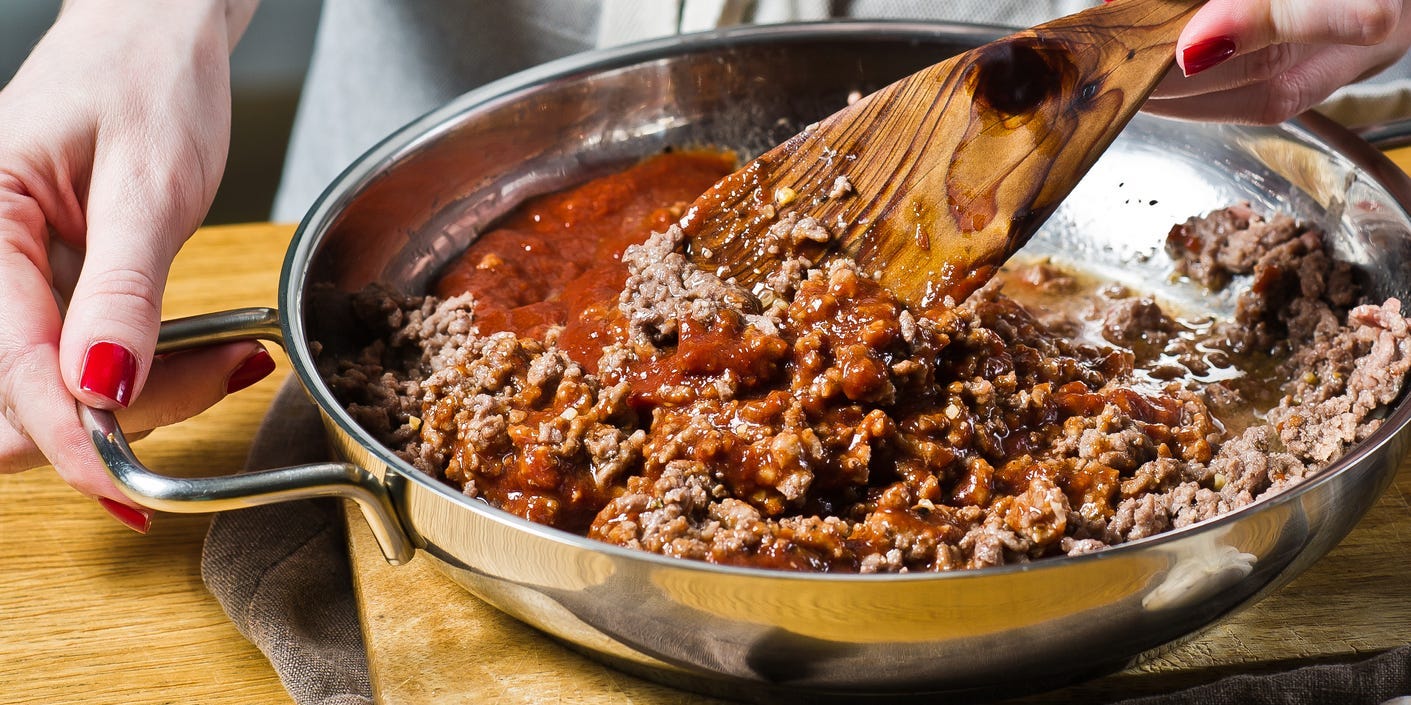 Chef cooking ground beef in a pan with sauce