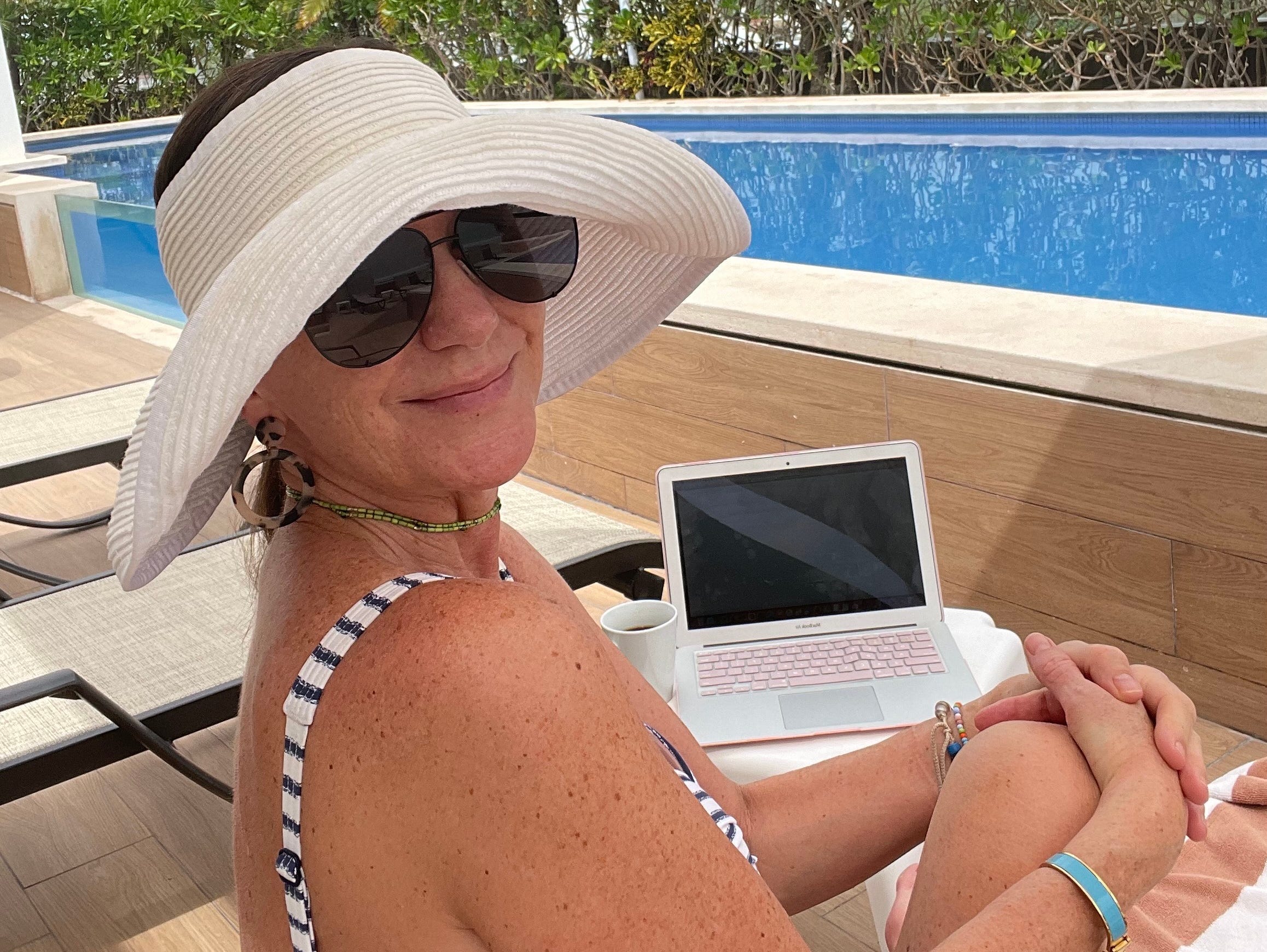 Denise Netzley embracing nomadic living, working on a laptop by the pool.