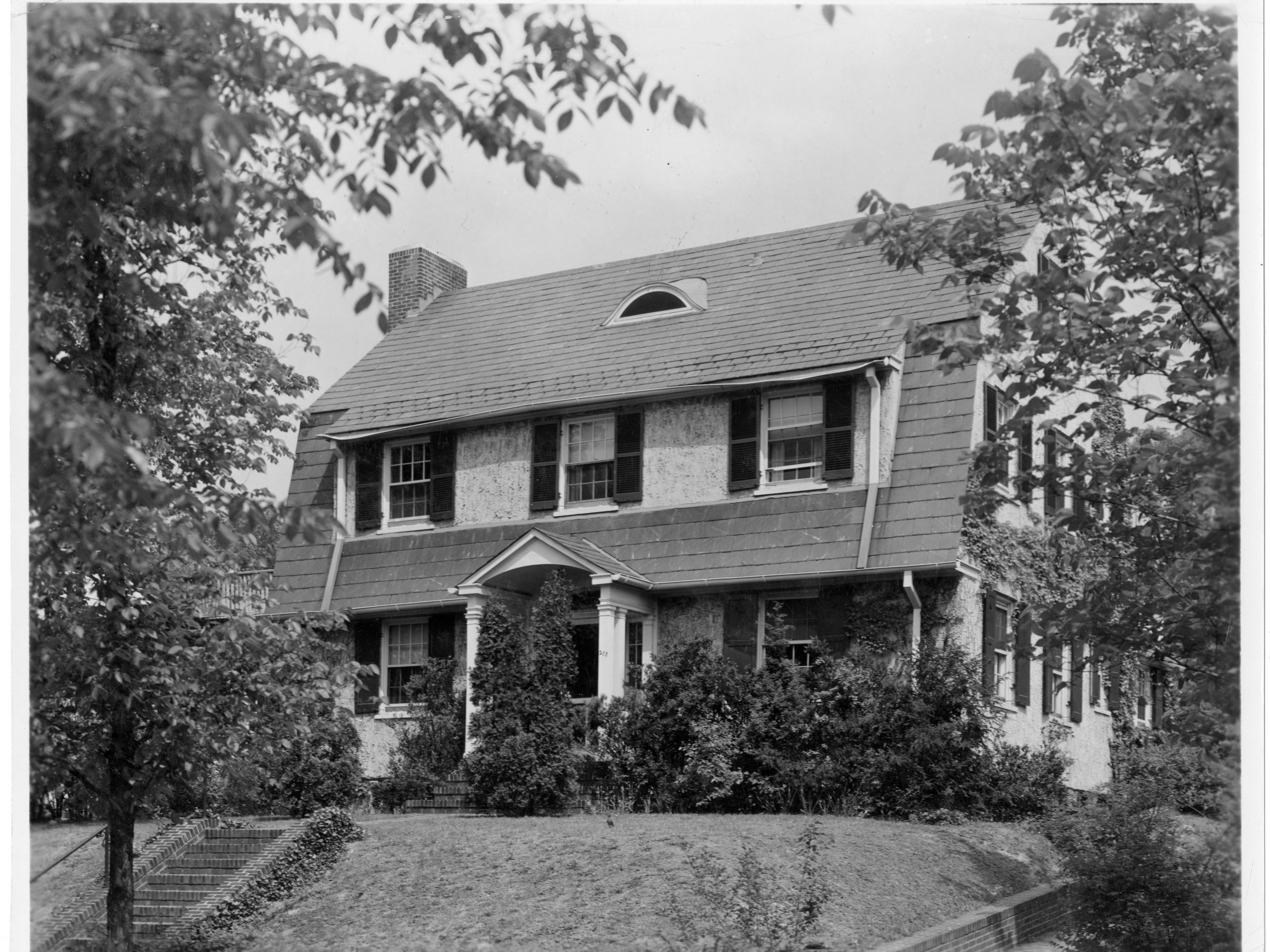 Black and white photo of a two-story home with trees.
