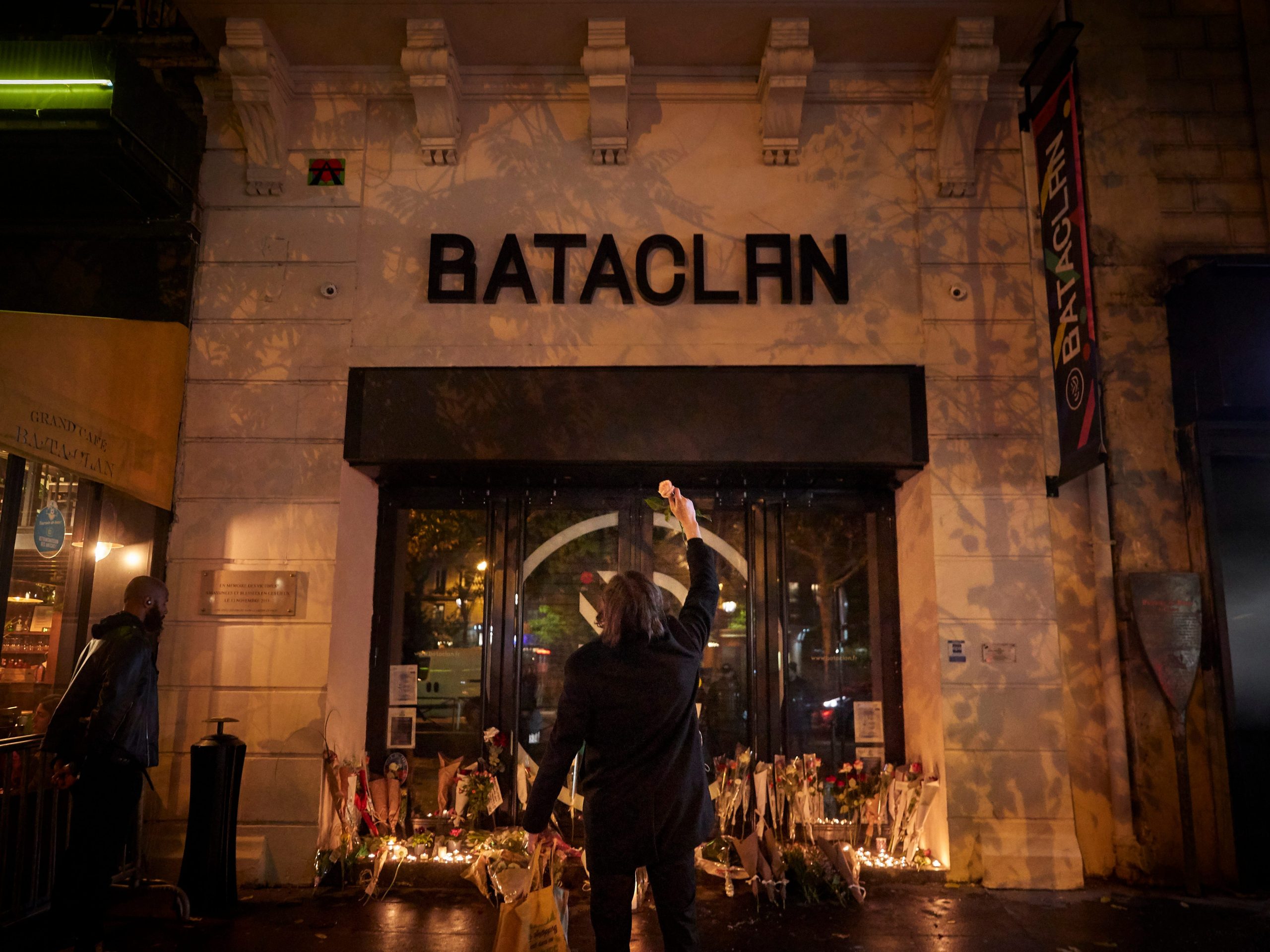 A Parisian holds a flower towards the Bataclan concert hall on the sixth anniversary of the 13th November 2015 Paris terror attacks on November 13, 2021 in Paris, France.