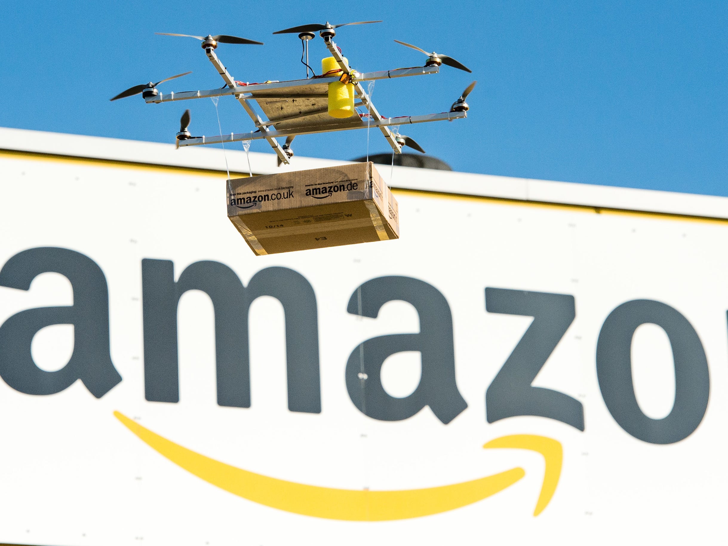 An Amazon drone flies in front of the company logo.