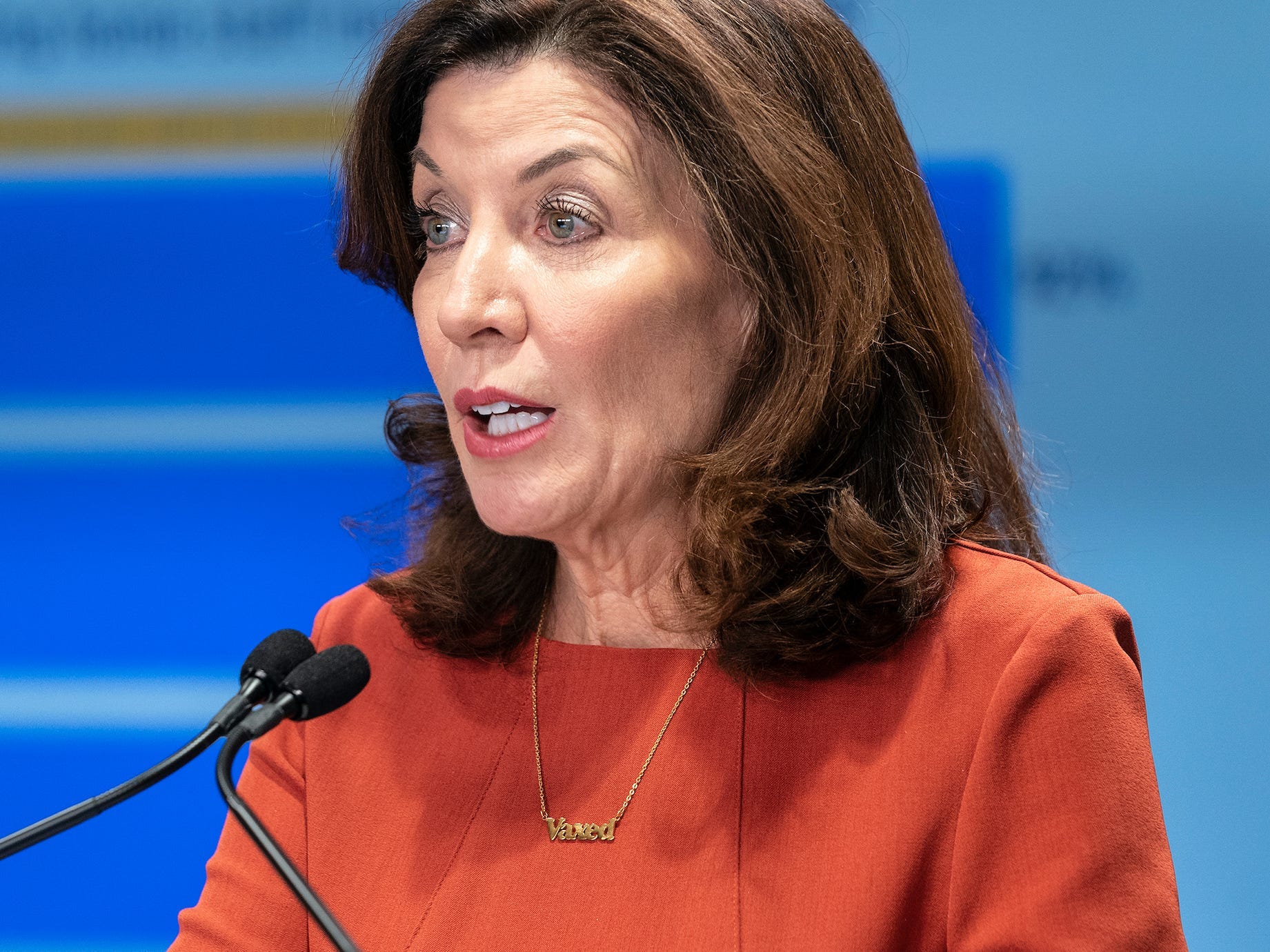 New York Governor Kathy Hochul speaks in front of a powerpoint presentation at a briefing.