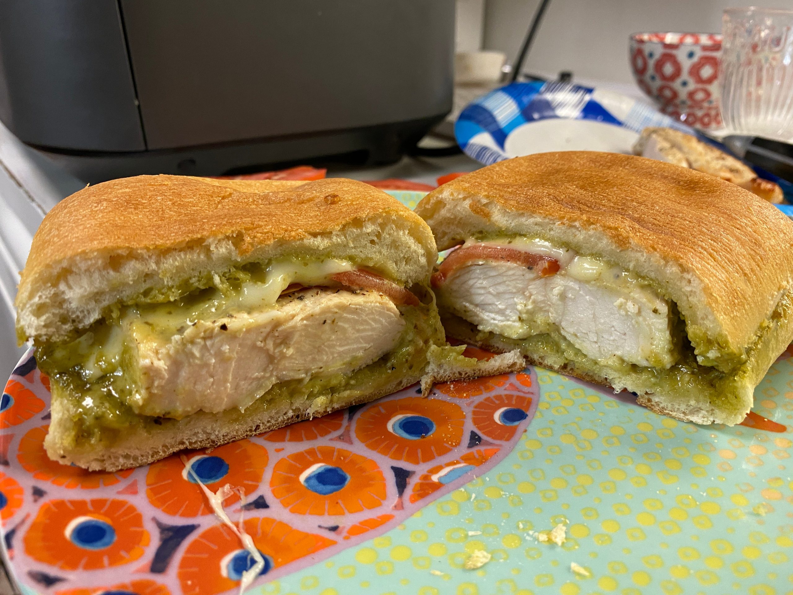 chicken, pesto-mayo and tomato on a sandwich  that's cut in half