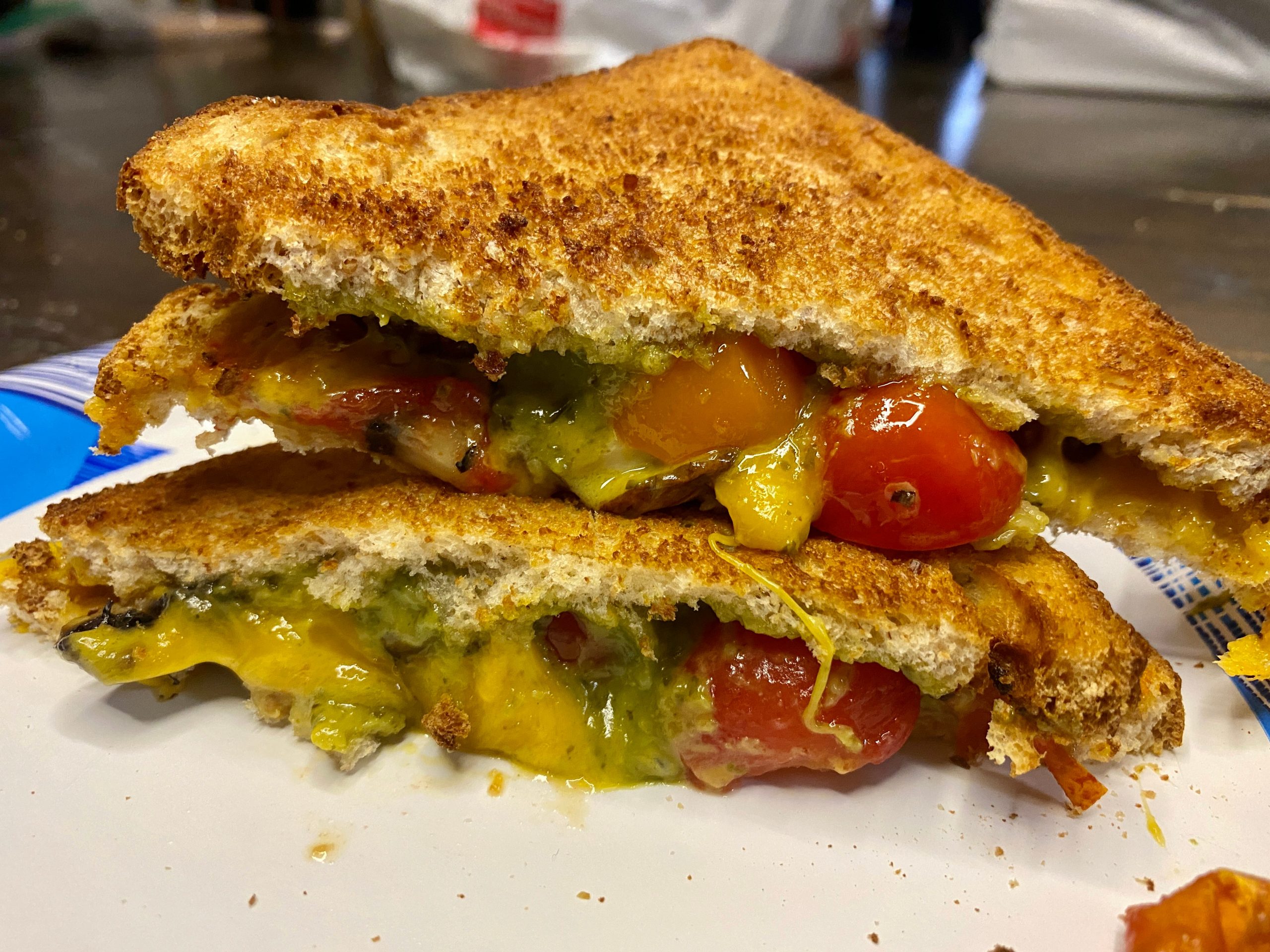 pesto, sliced cherry tomatoes, and mushrooms on bread, toasted and sliced in half