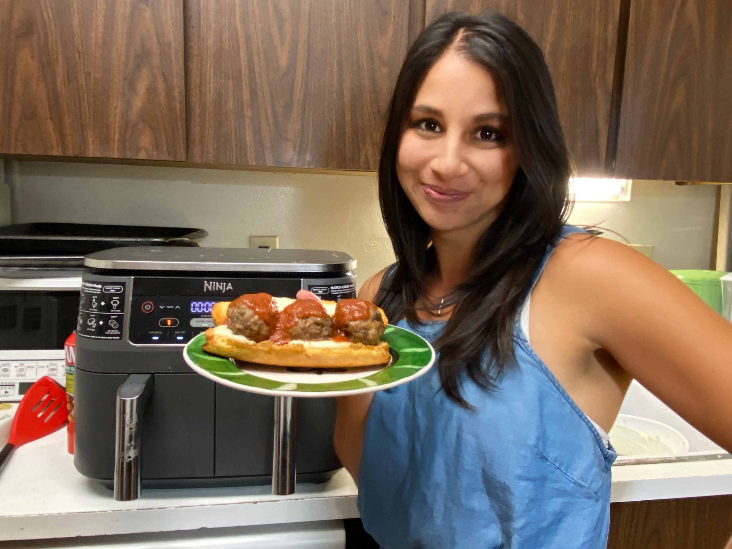 the writer posing with a meatball sub in front of an air fryer