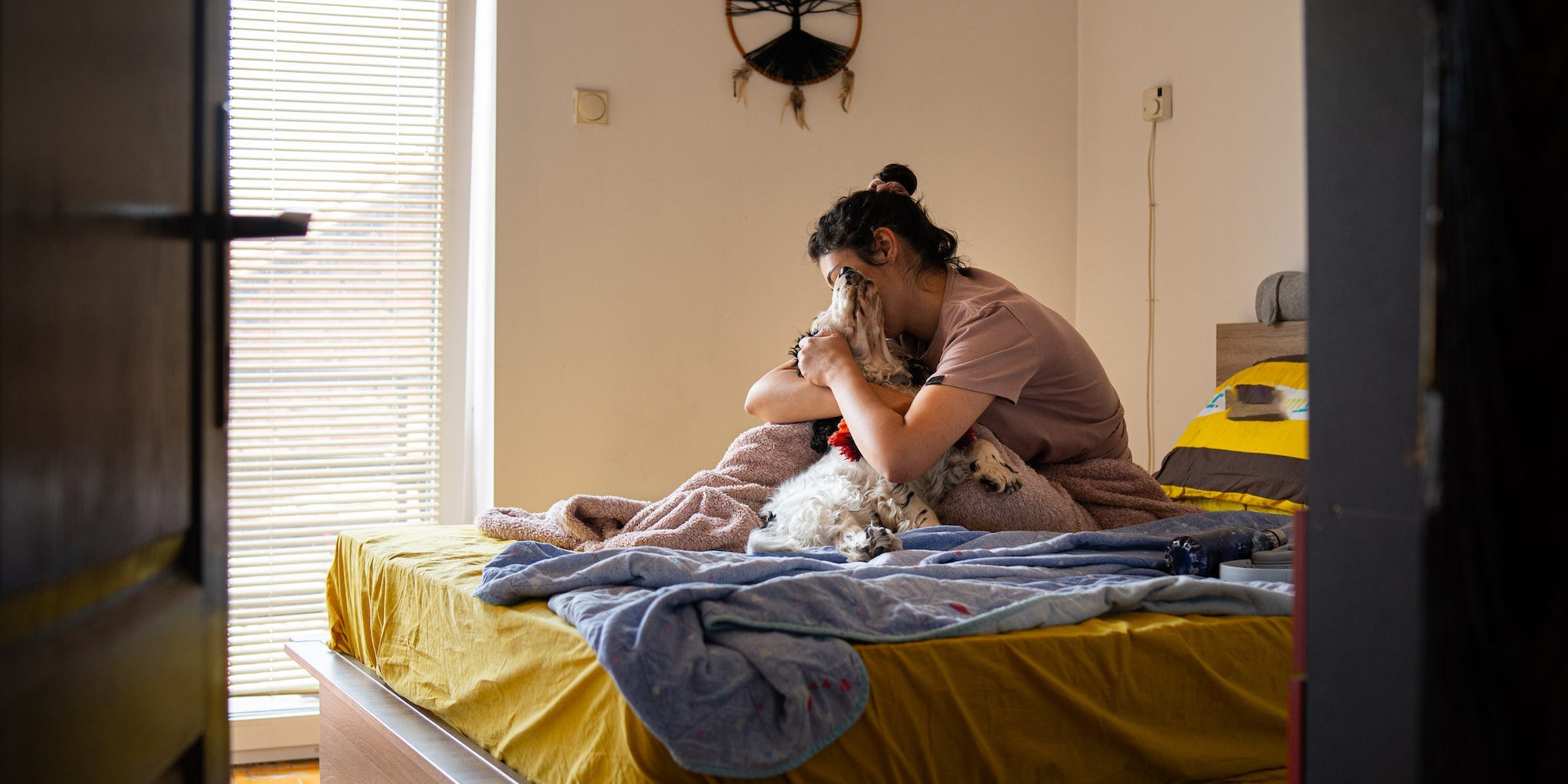 A woman cuddles with her dog on a bed.
