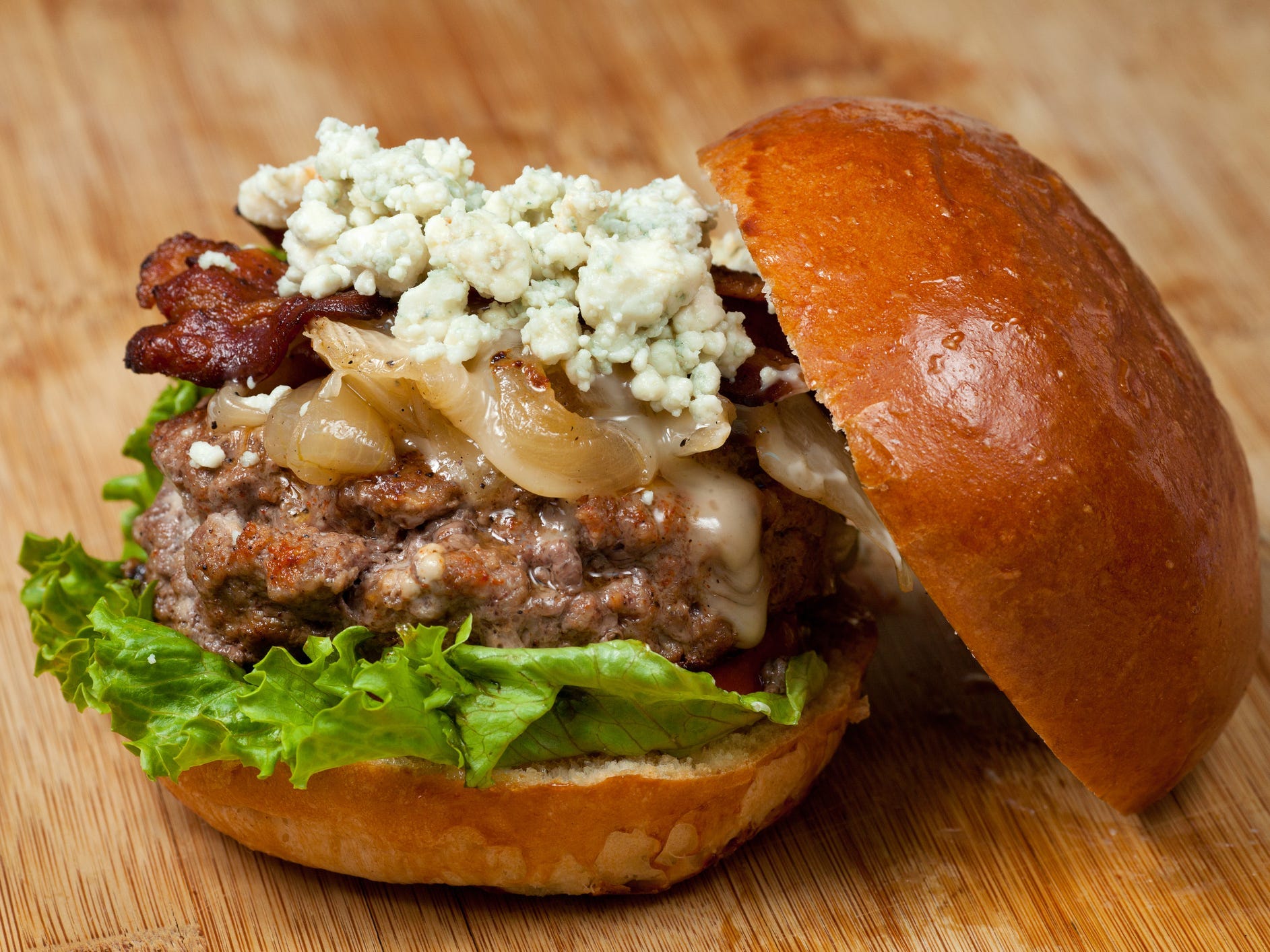 A hamburger topped with blue cheese, bacon, and caramelized onions