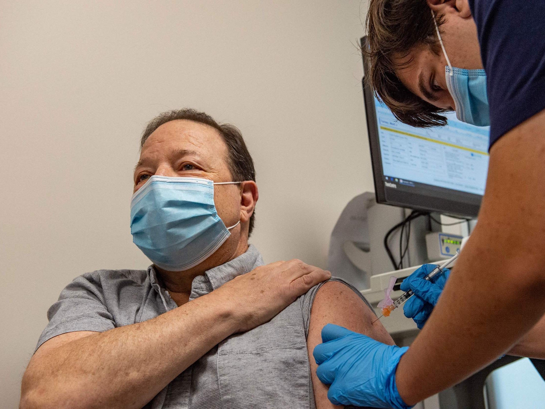 masked medic gives masked patient a vaccine shot in arm