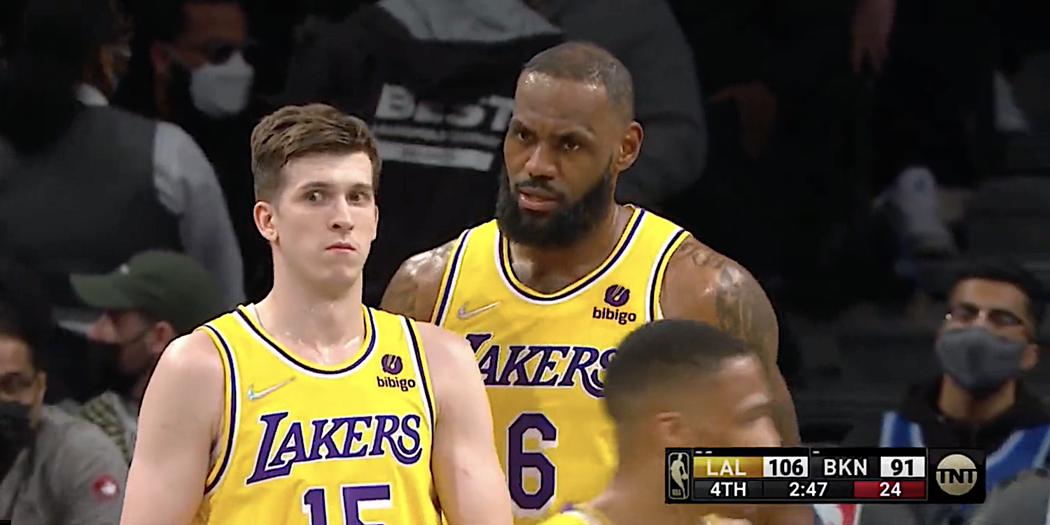 Austin Reaves looks confused as LeBron James speaks to him during a game.