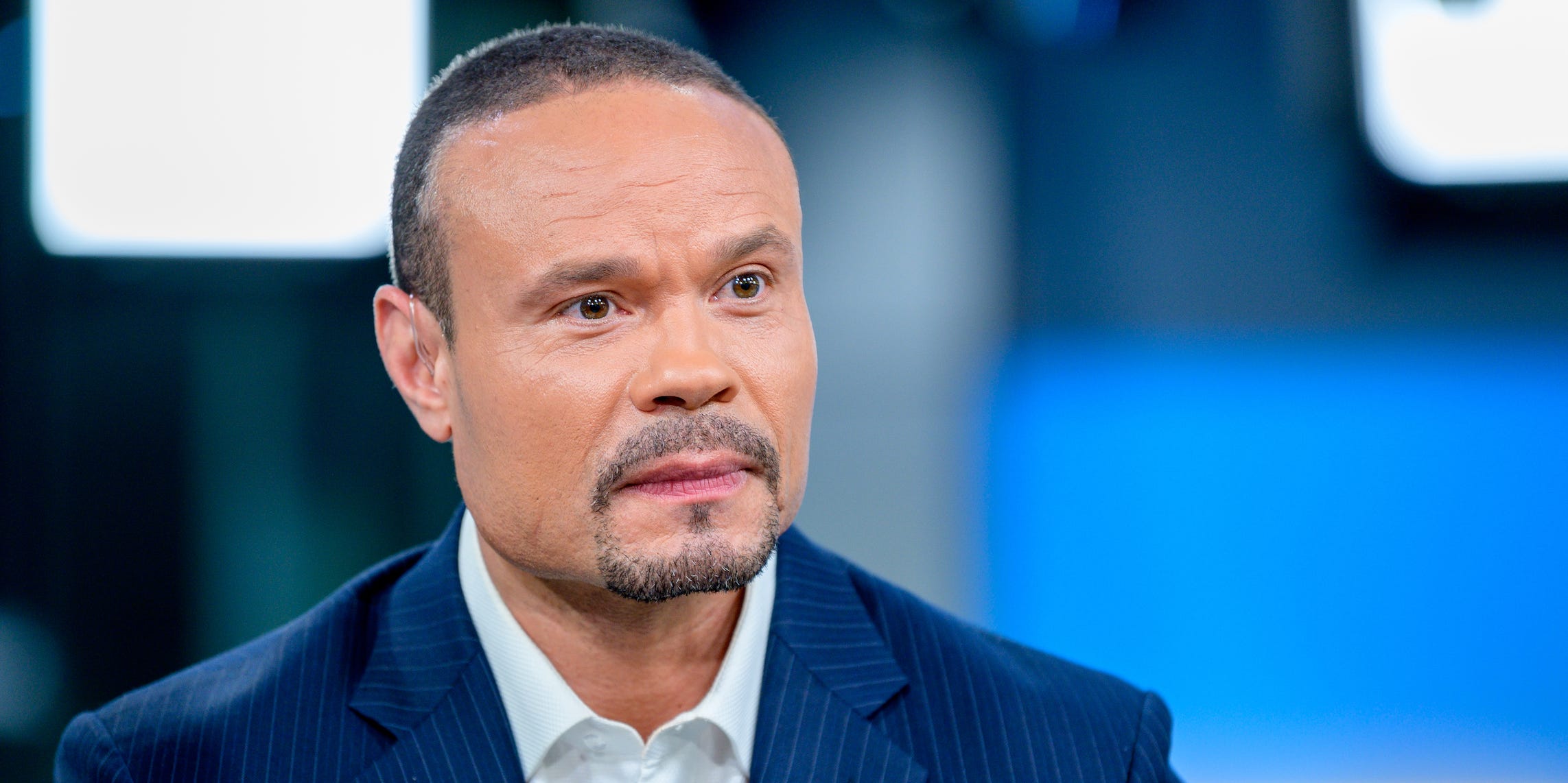 Dan Bongino looks off to the side of a camera on set.