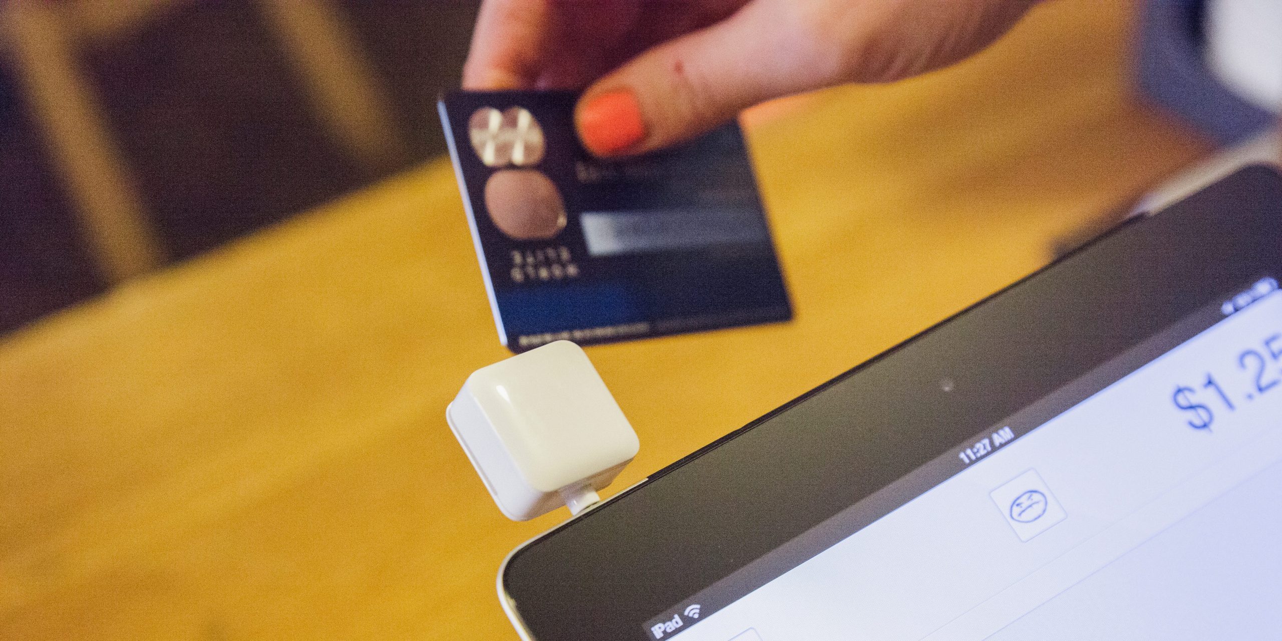 A credit card is being swiped on a Square mobile payment terminal.