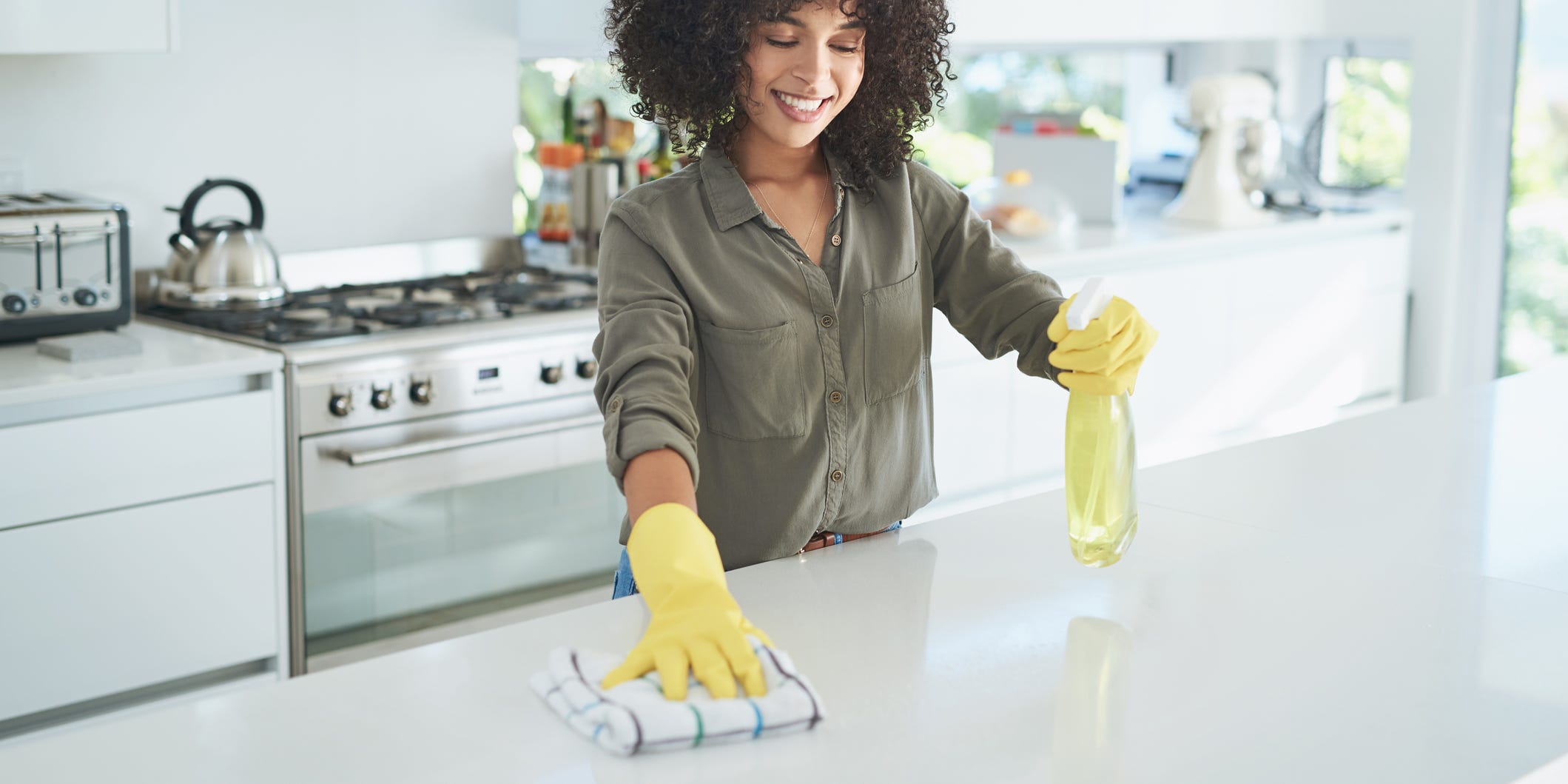 A person using a spray bottle and a rag to clean a kitchen counter