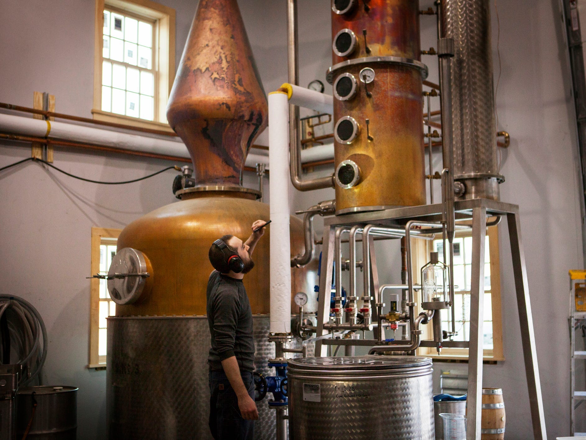 Man looking at a copper still at a distillery