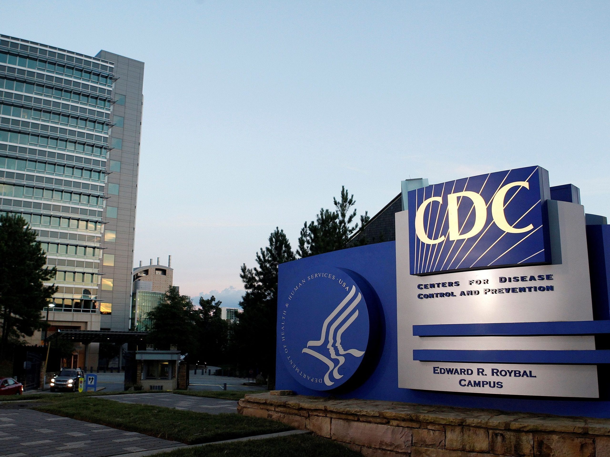 The blue-and-white CDC sign in front of the agency's Atlanta headquarters at sunset