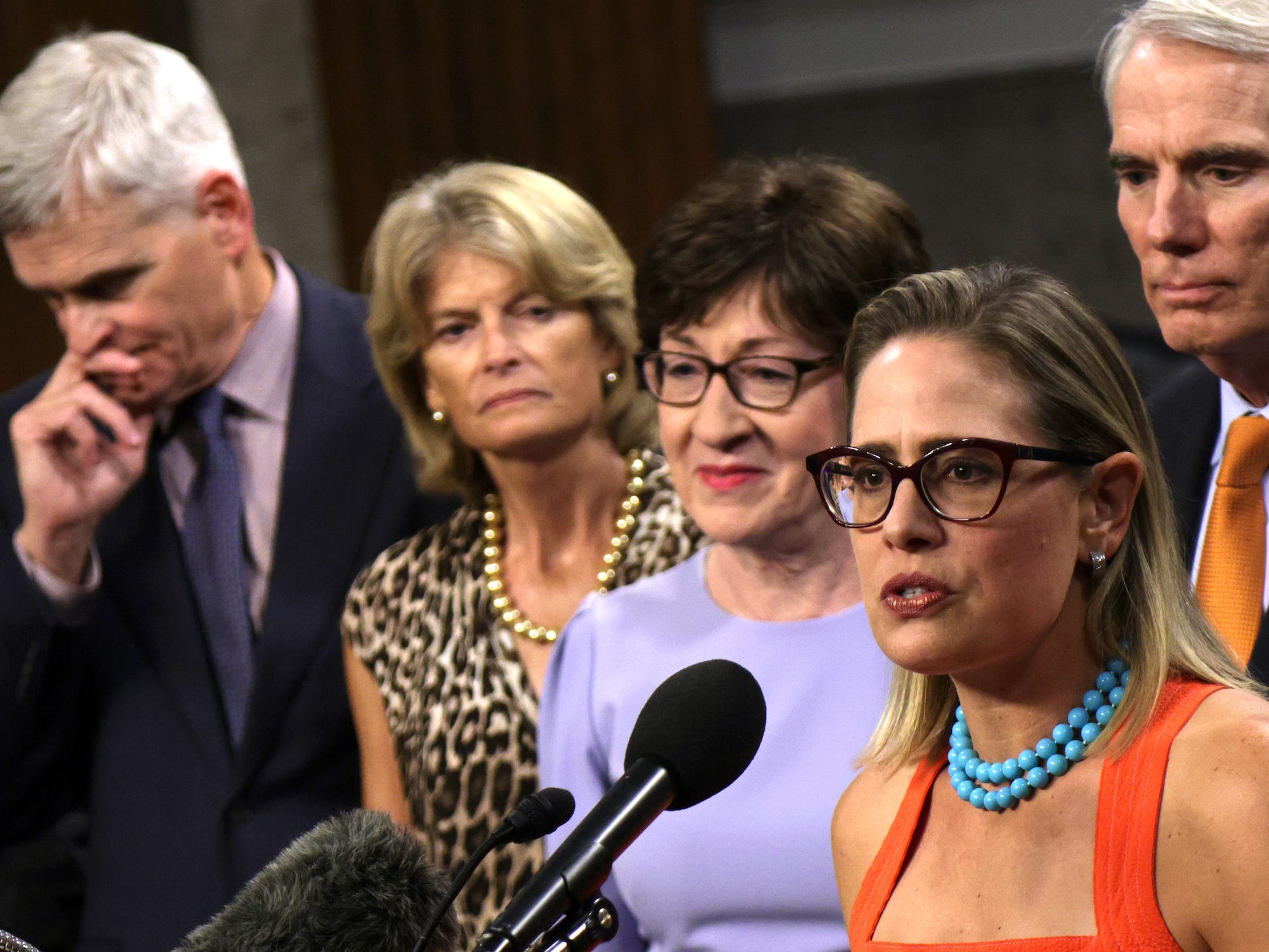 Democratic Sen. Kyrsten Sinema of Arizona speaks as Republican Sens. Lisa Murkowski of Alaska and Susan Collins of Maine stand by on Capitol Hill on July 28, 2021.