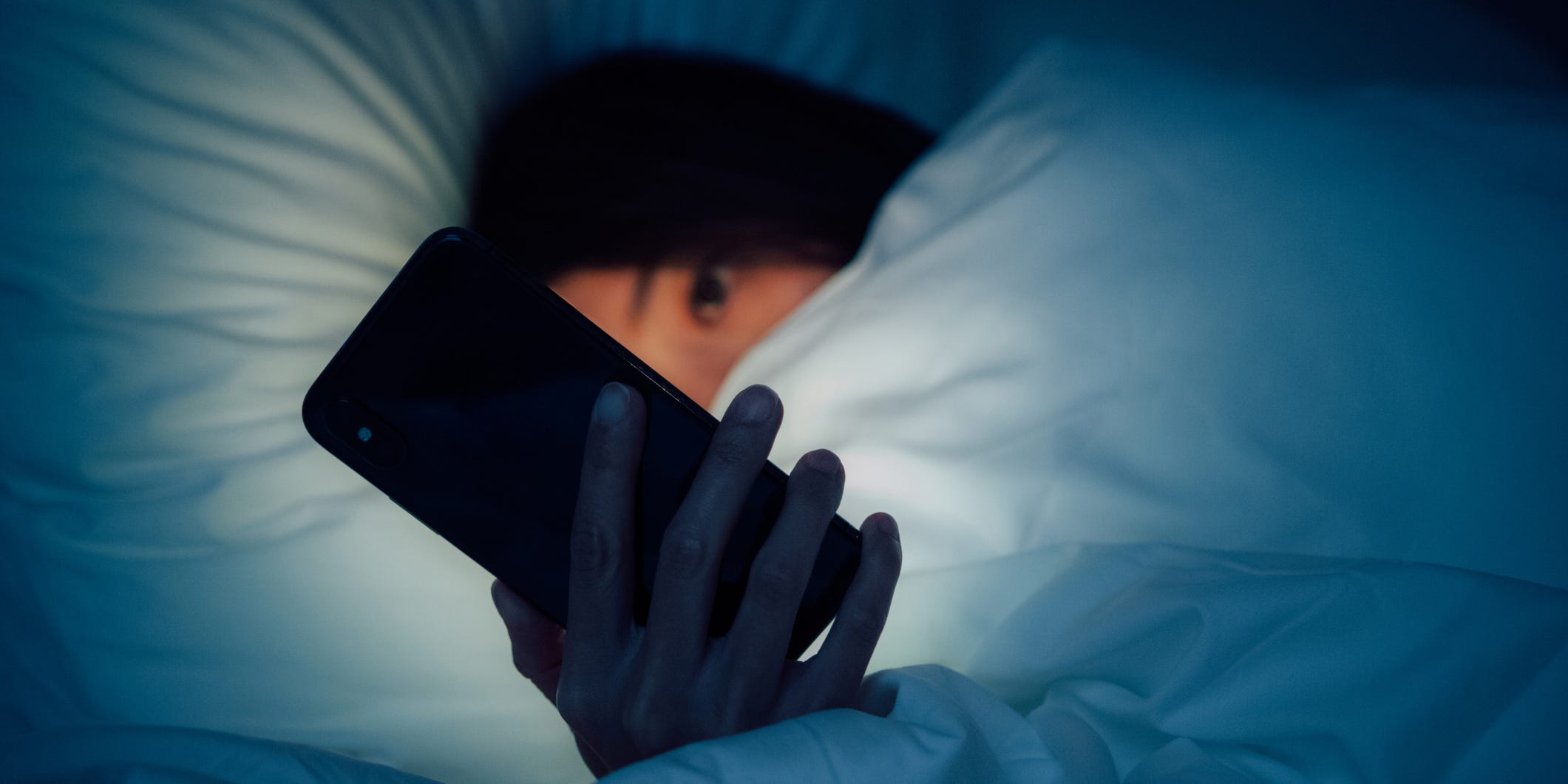 person looking at phone in bed