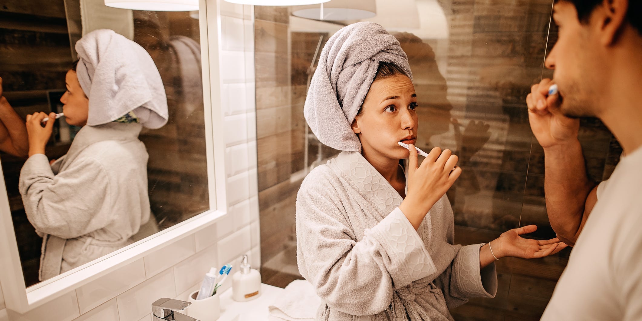 a couple argues in their bathroom while both brushing their teeth