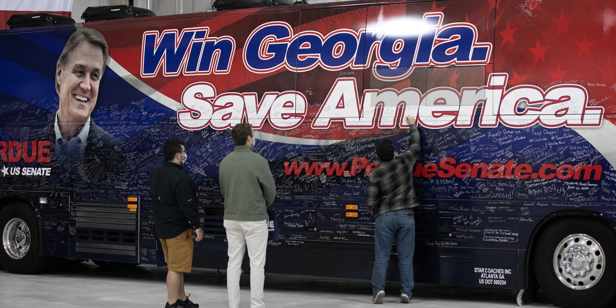 Supporters sign the campaign bus for Sen. David Perdue (R-GA) during a campaign rally at Peachtree Dekalb Airport on December 14, 2020 in Atlanta, Georgia
