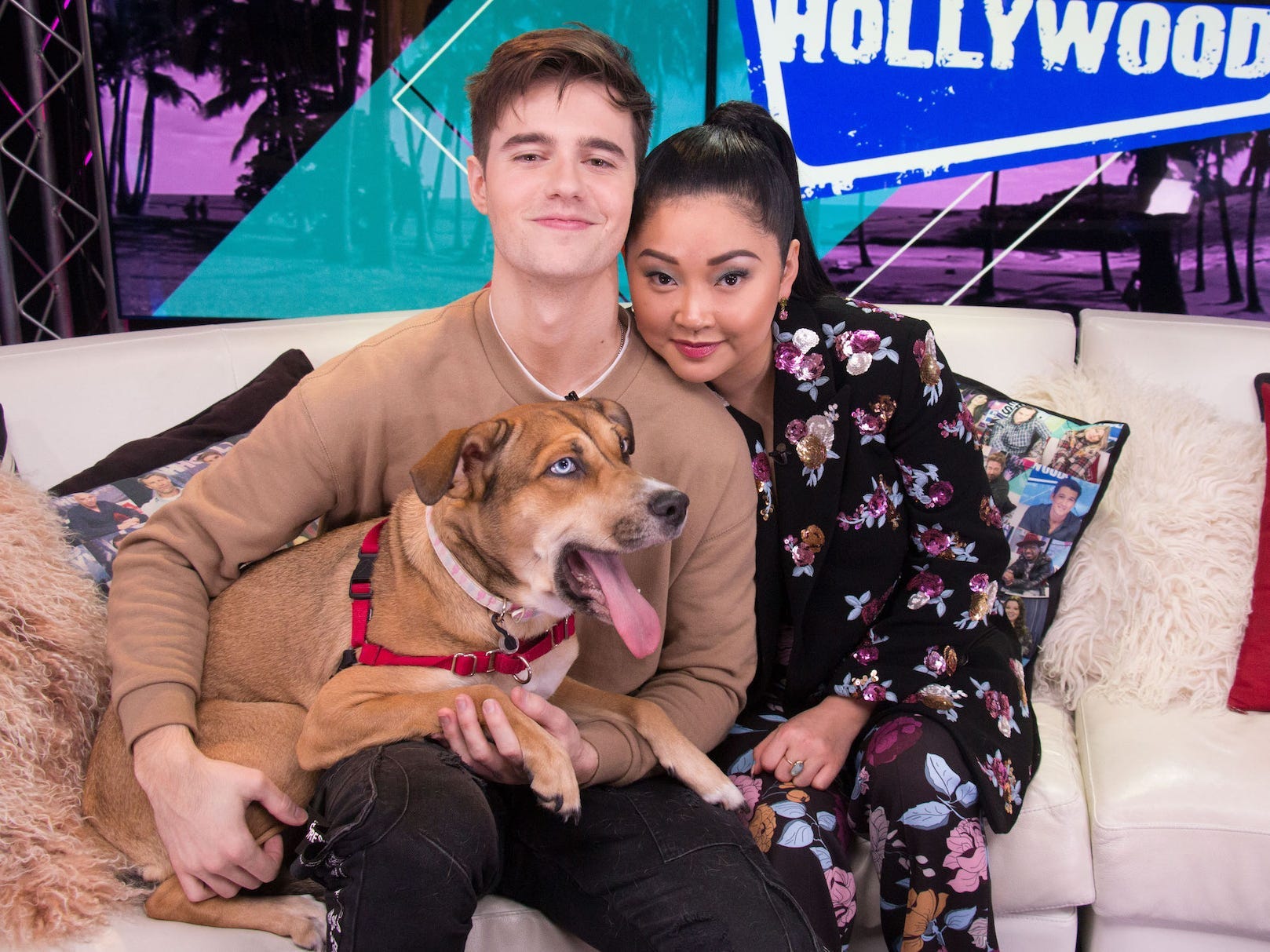 Anthony De La Torre and Lana Condor smile with a dog on their laps.