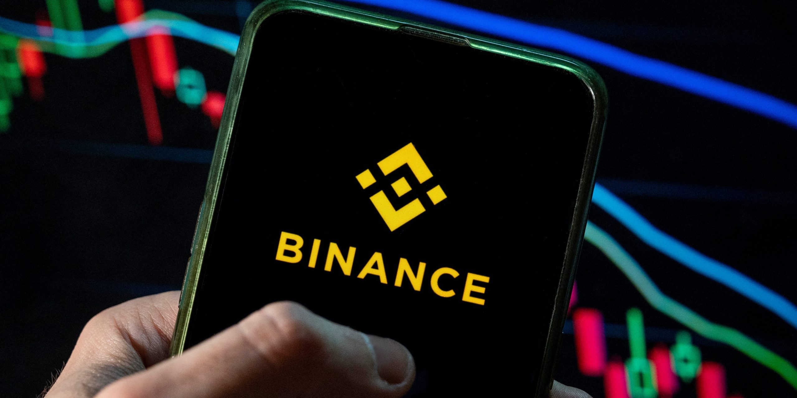 In this photo illustration the cryptocurrency exchange trading platform Binance logo seen displayed on a smartphone with an economic stock exchange index graph in the background.