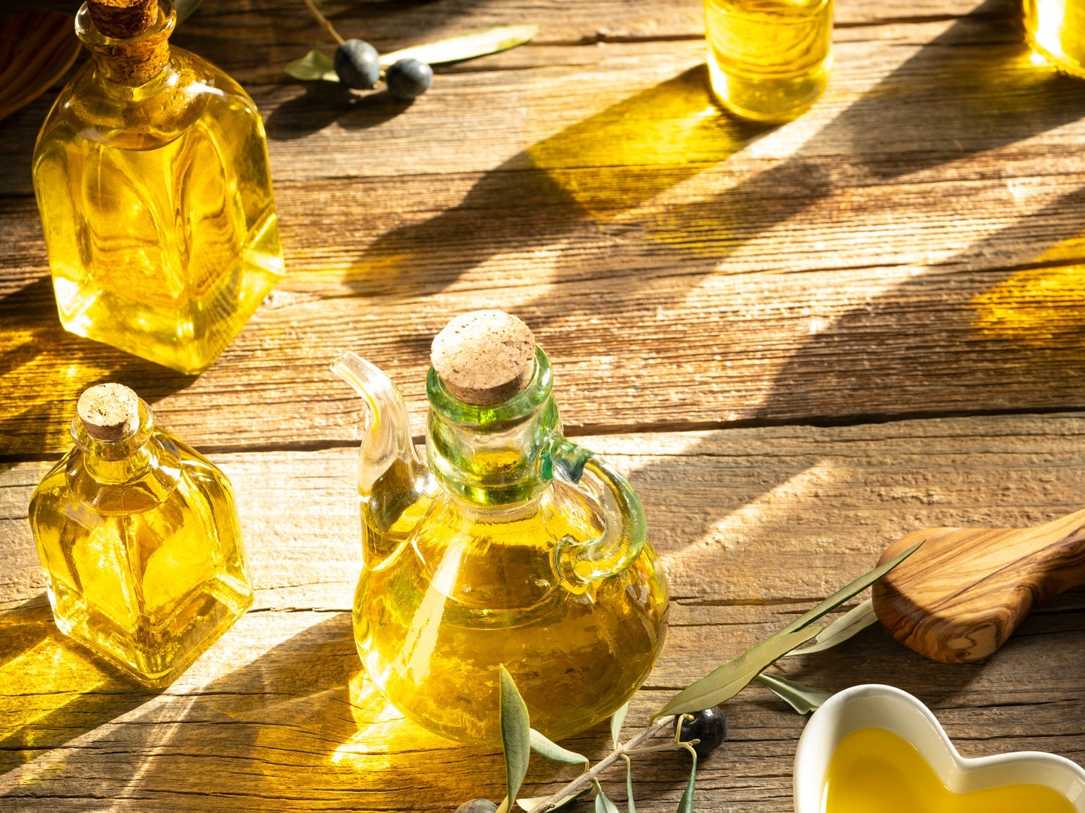 Olive oil bottles arranged to the left, lit up by the sun