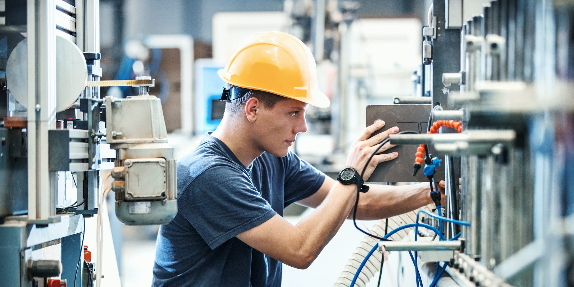 employee at a factory plant operating a production line machine and setting it for work