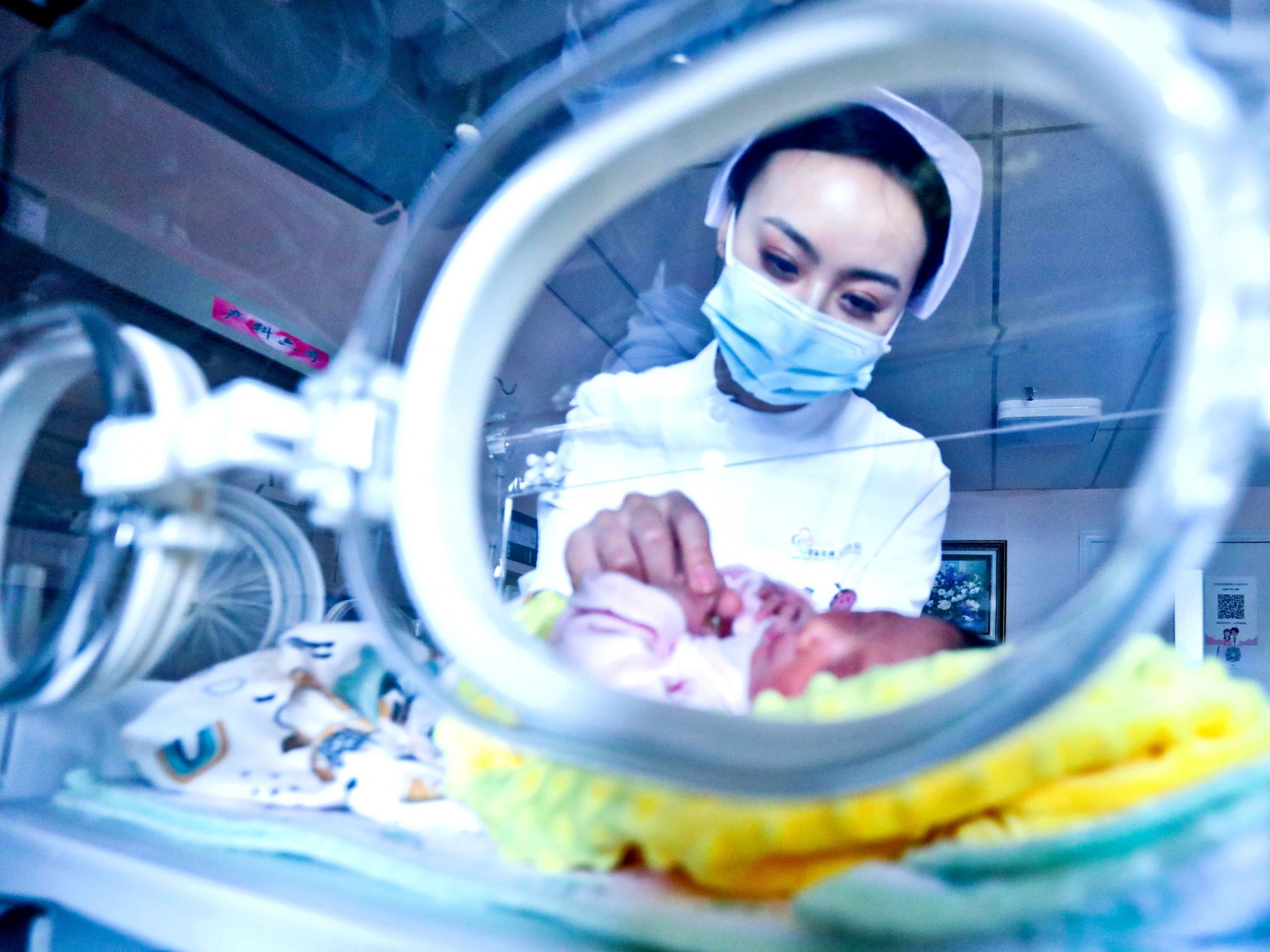 A picture of a masked medical worker attending to a baby in China.