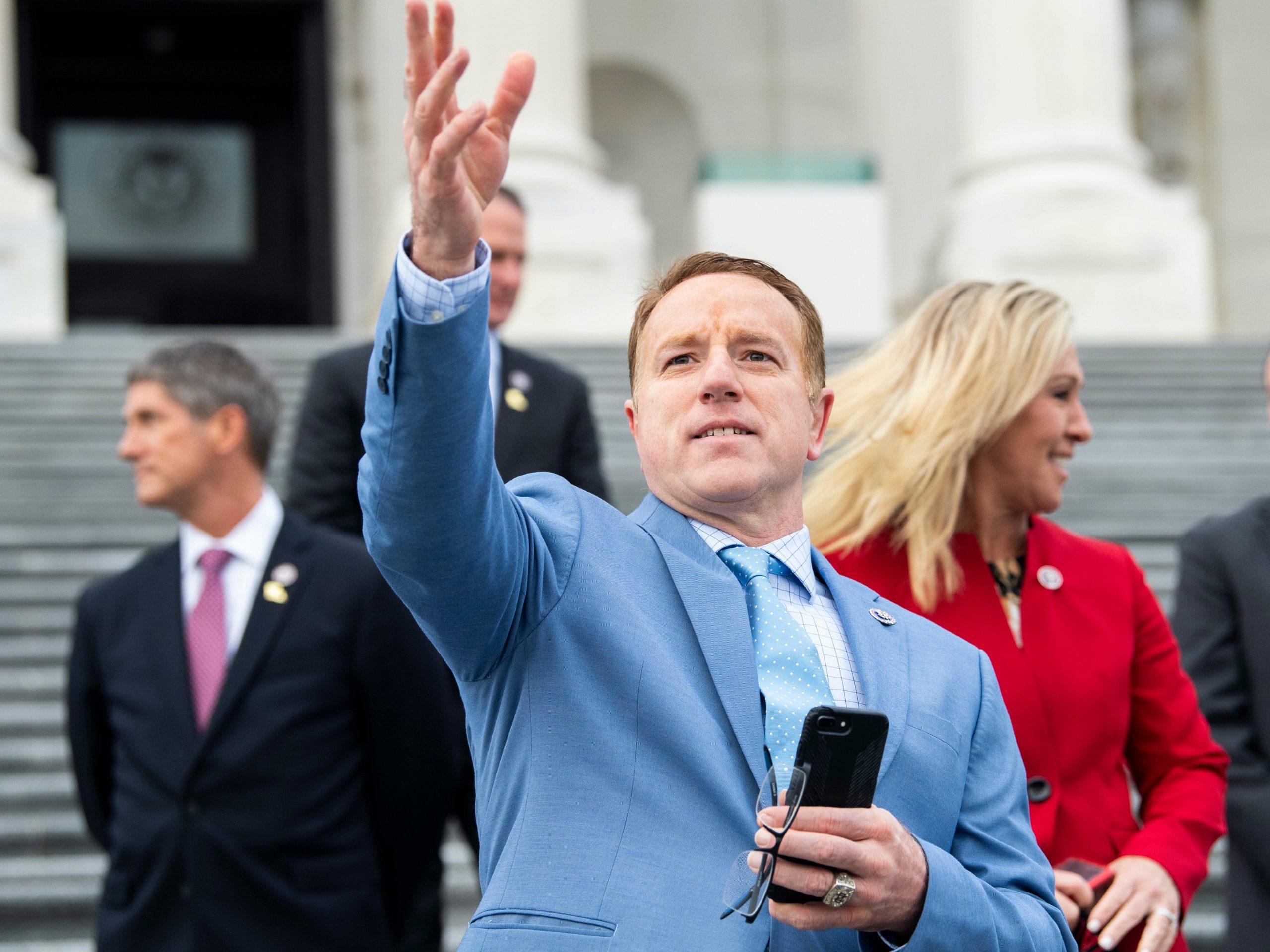 Rep. Pat Fallon waving his right hand and wearing a light blue suit during a group photo with freshman members of the House Republican Conference.