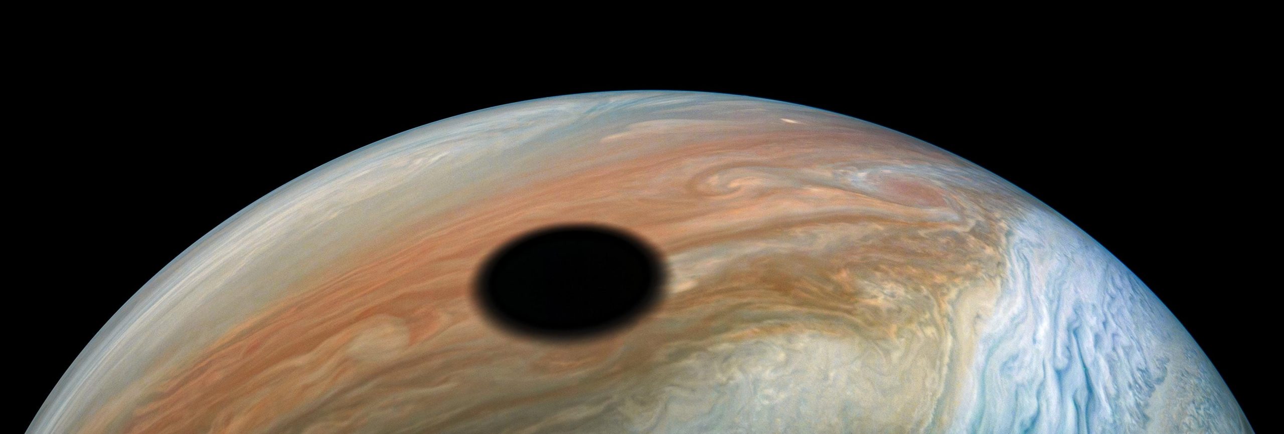 jupiter moon io casts shadow over planet's colorful bands