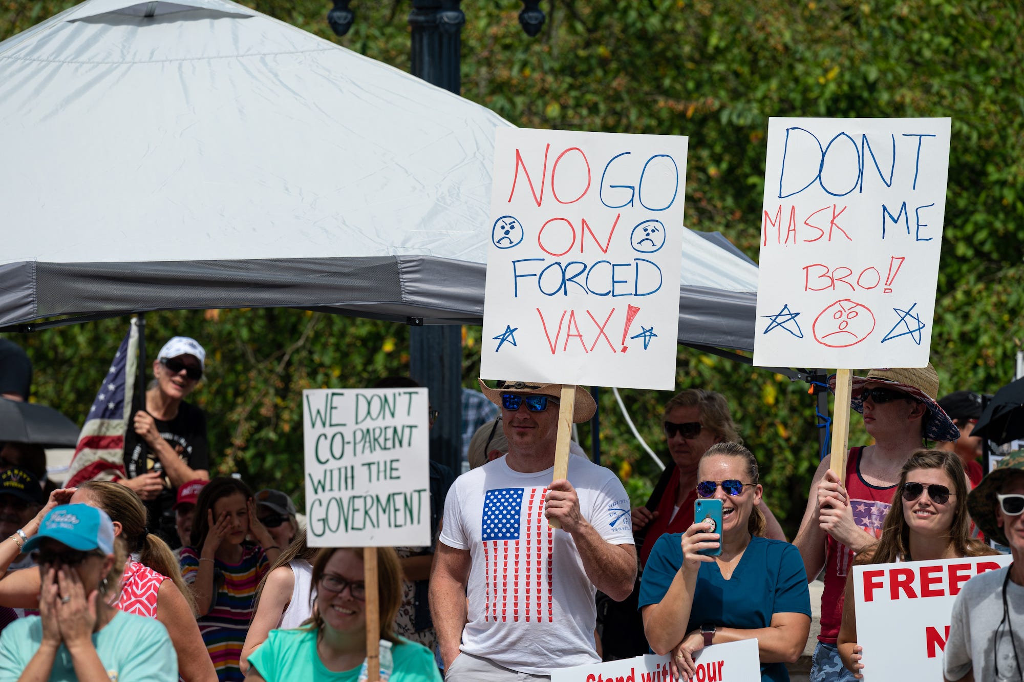 People display signs protesting mask and vaccine mandates during the Kentucky Freedom Rally at the capitol building on August 28, 2021 in Frankfort, Kentucky.