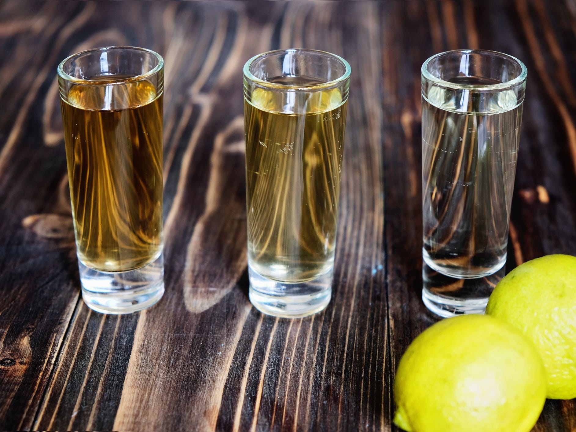 Three different types of tequila in shot glasses on a wooden board