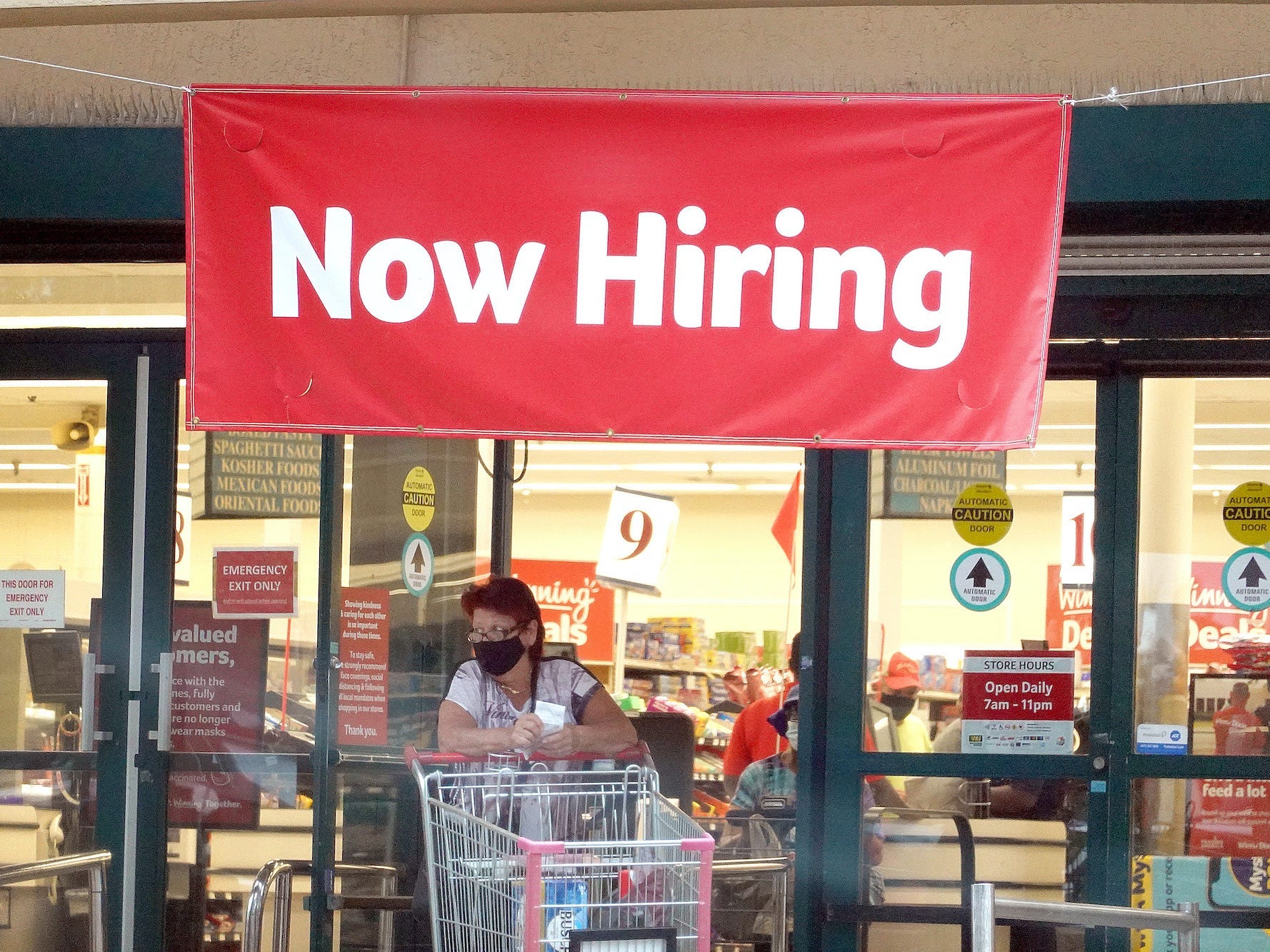 A Now Hiring sign hangs near the entrance to a Winn-Dixie Supermarket