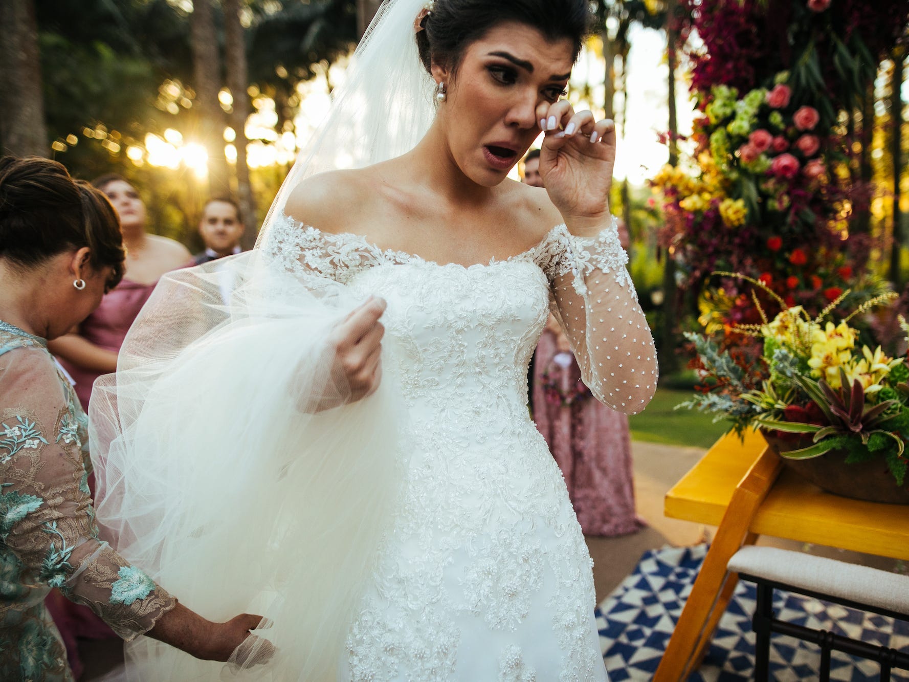 A sad bride wiping away a tear at her wedding.