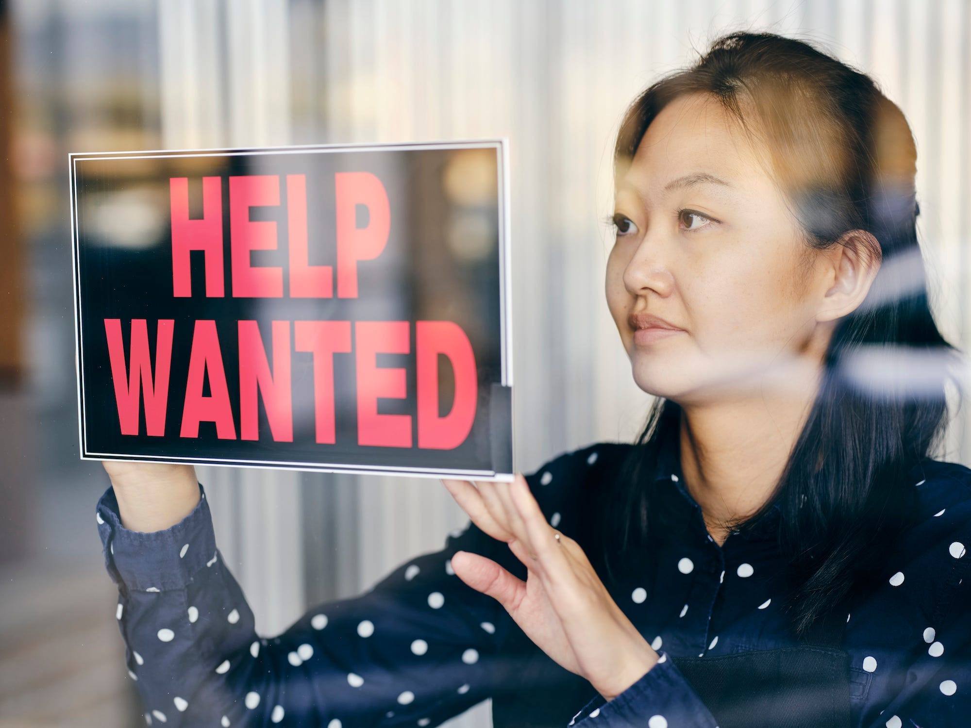 Business Owner Putting Up Help Wanted Sign