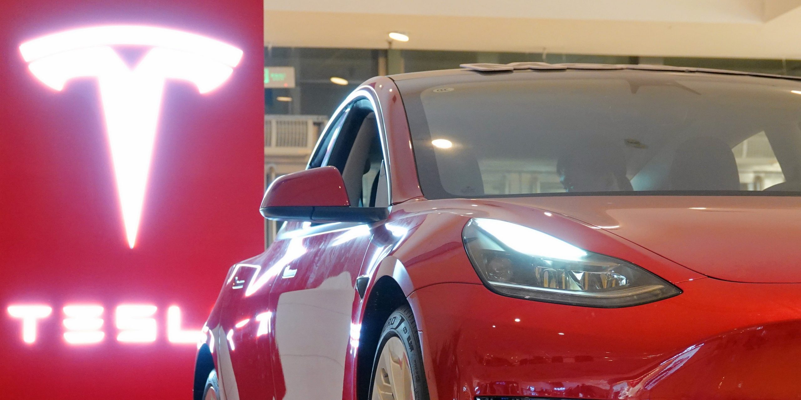 A red Tesla Model 3 in a showroom.