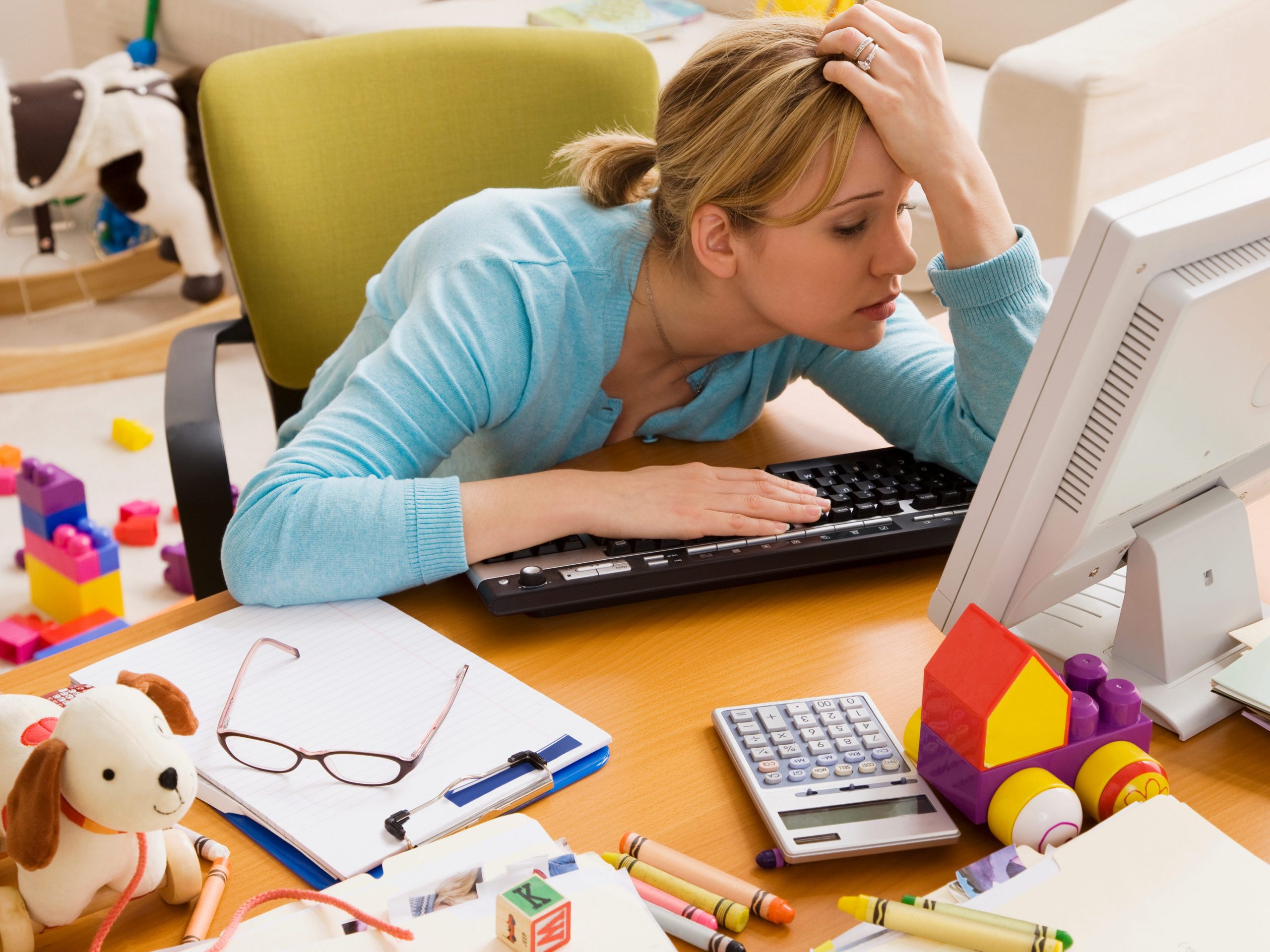 Women stares at computer screen surrounded by toys.