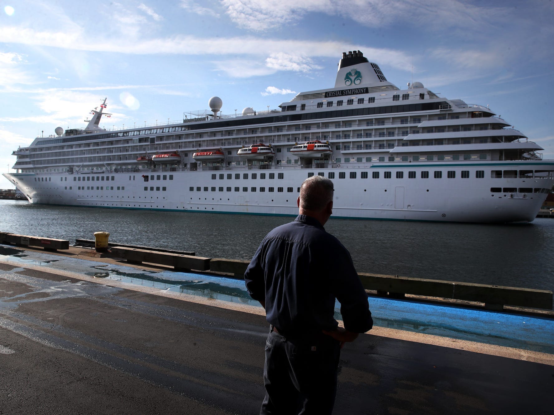 A pedestrian watches as the Crystal Symphony cruise ship arrives at Flynn Cruiseport in Boston, MA on August 18, 2021.