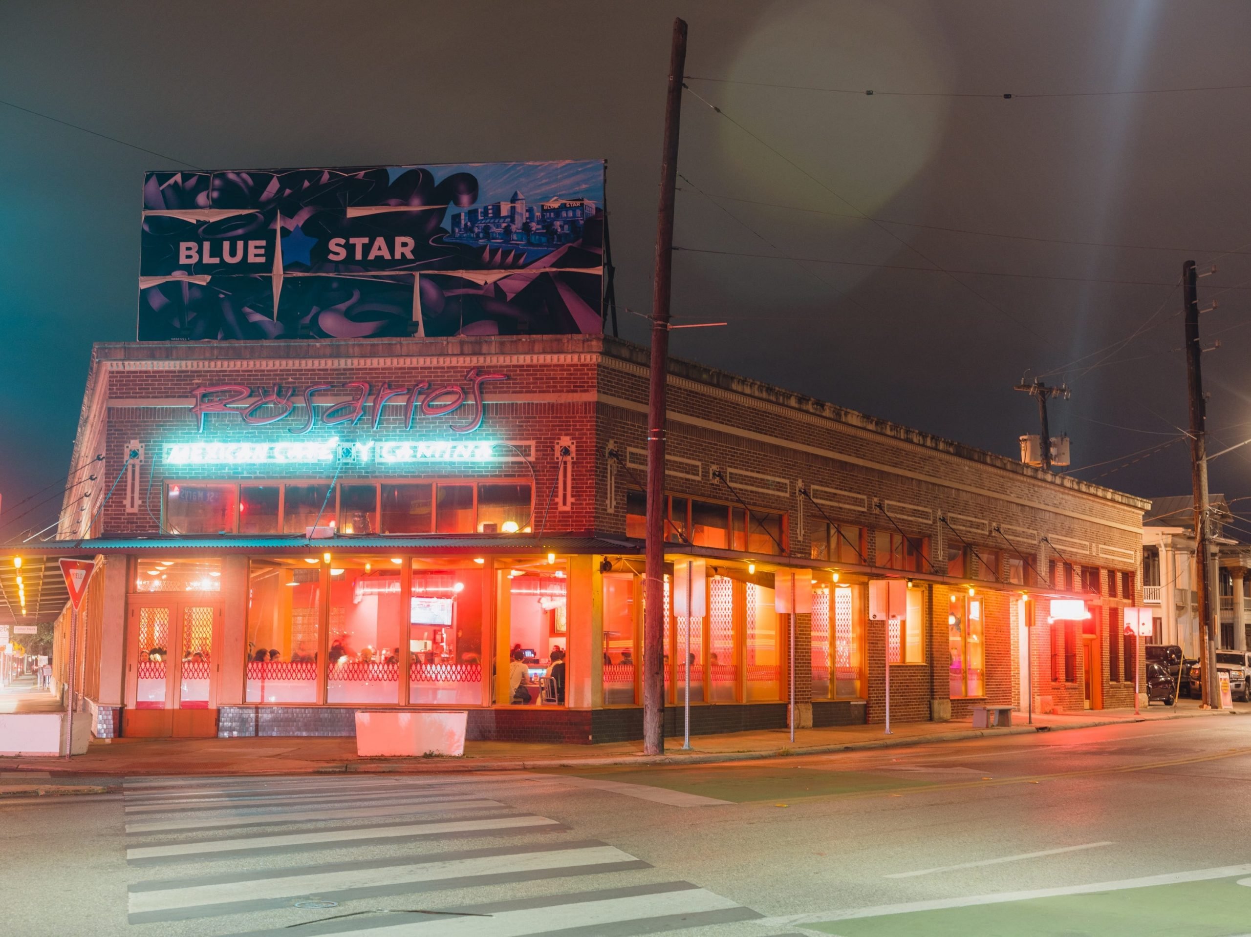 A street view of a lit up restaurant at night.