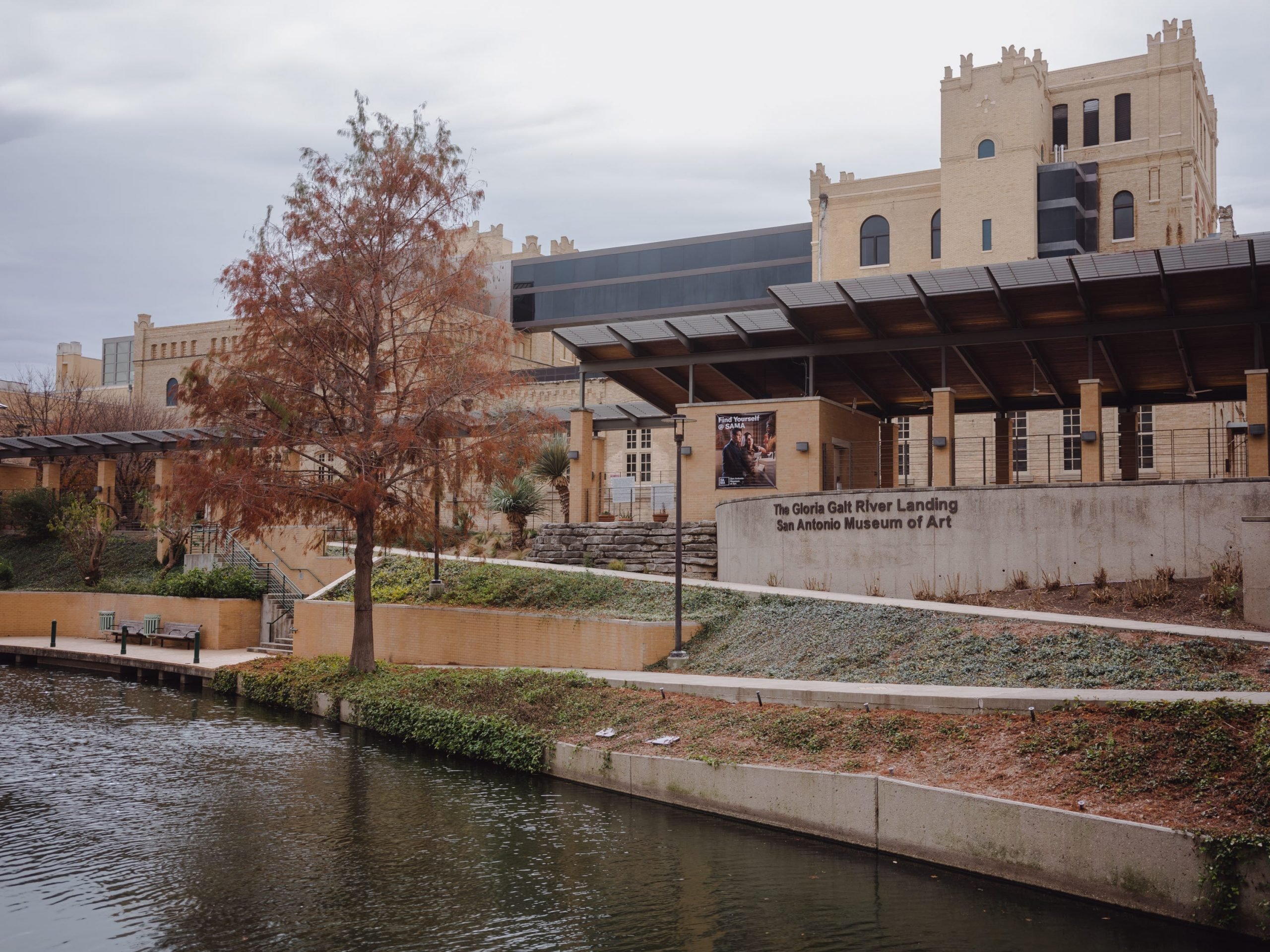 A river in front of a large tan building.