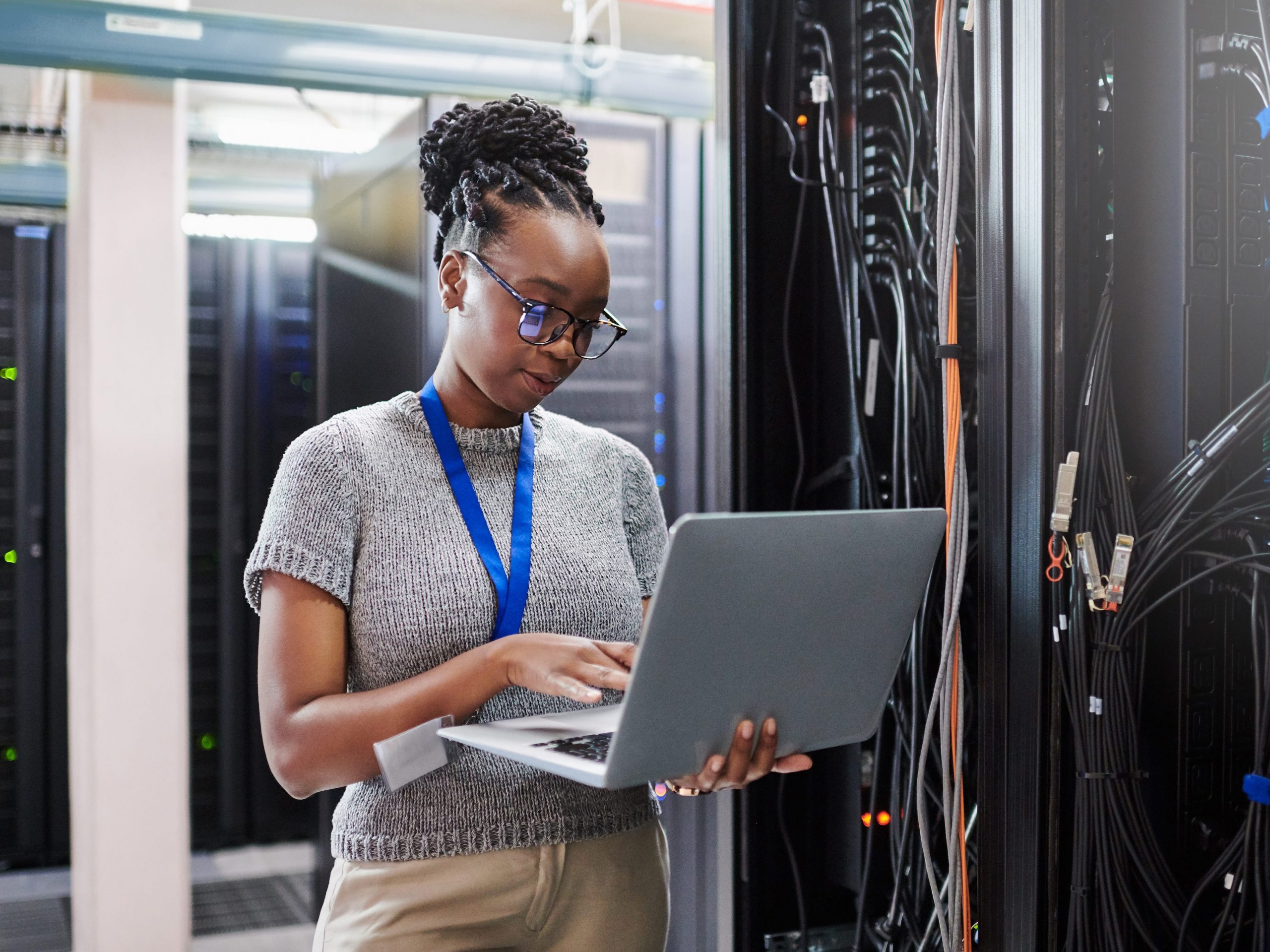 Shot of a young woman using a laptop in a server room