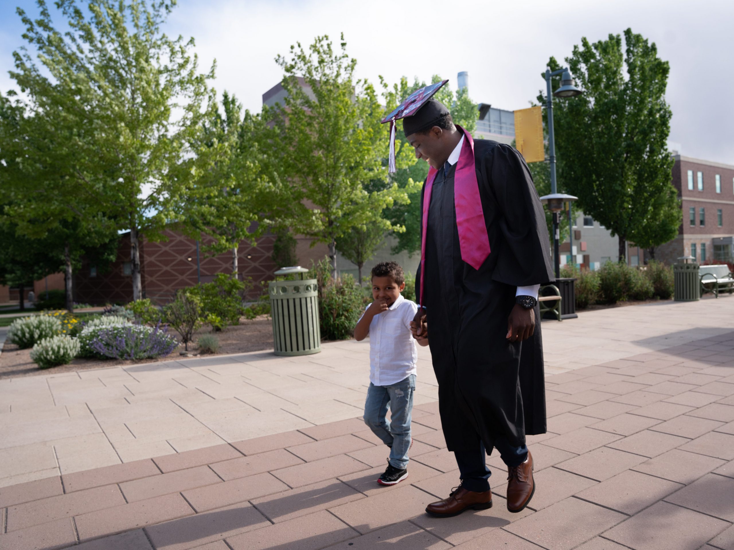 Adult male graduate walking with son