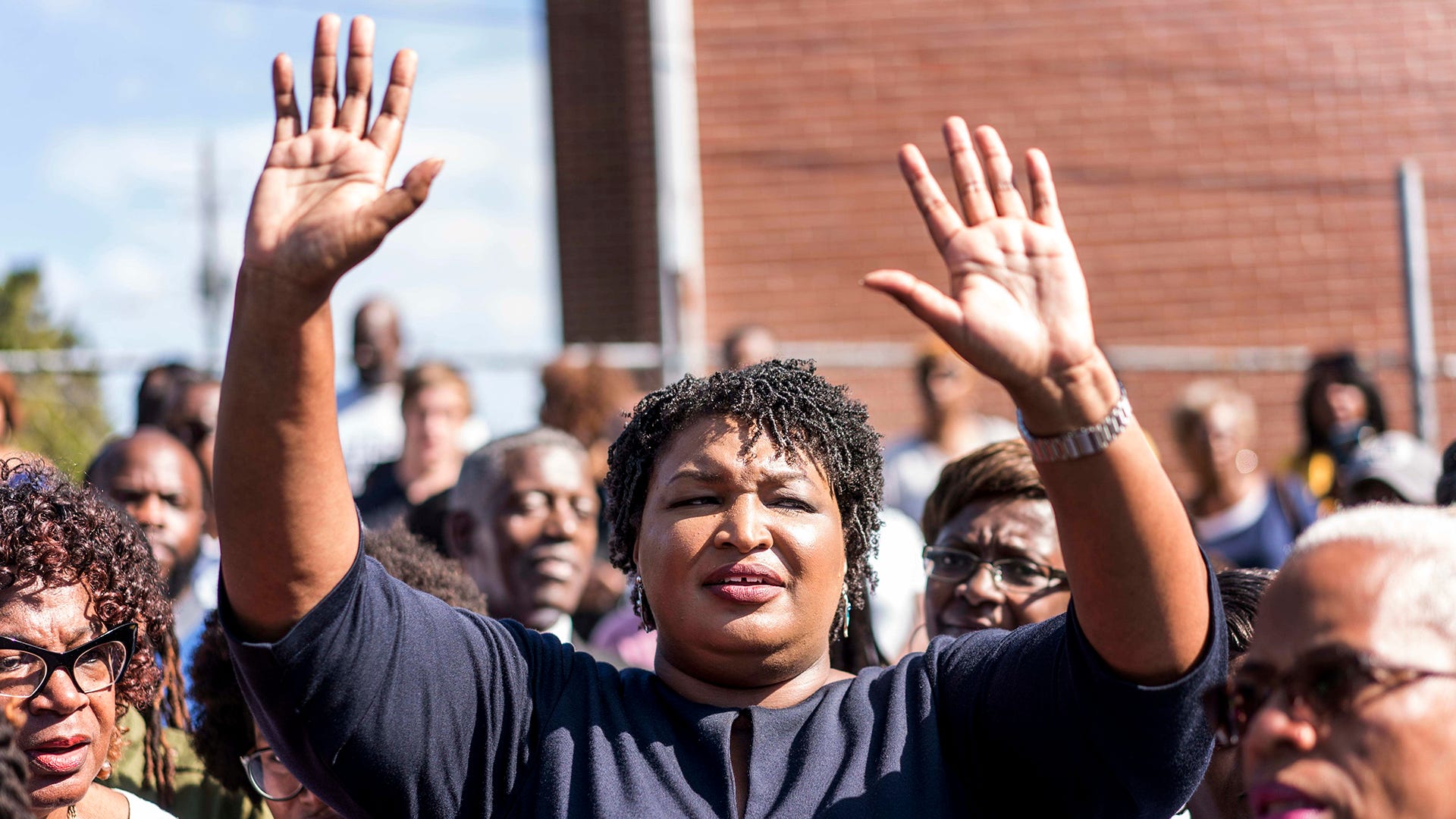 Stacey Abrams has her hands raised at a Gubernatorial campaign event in 2018