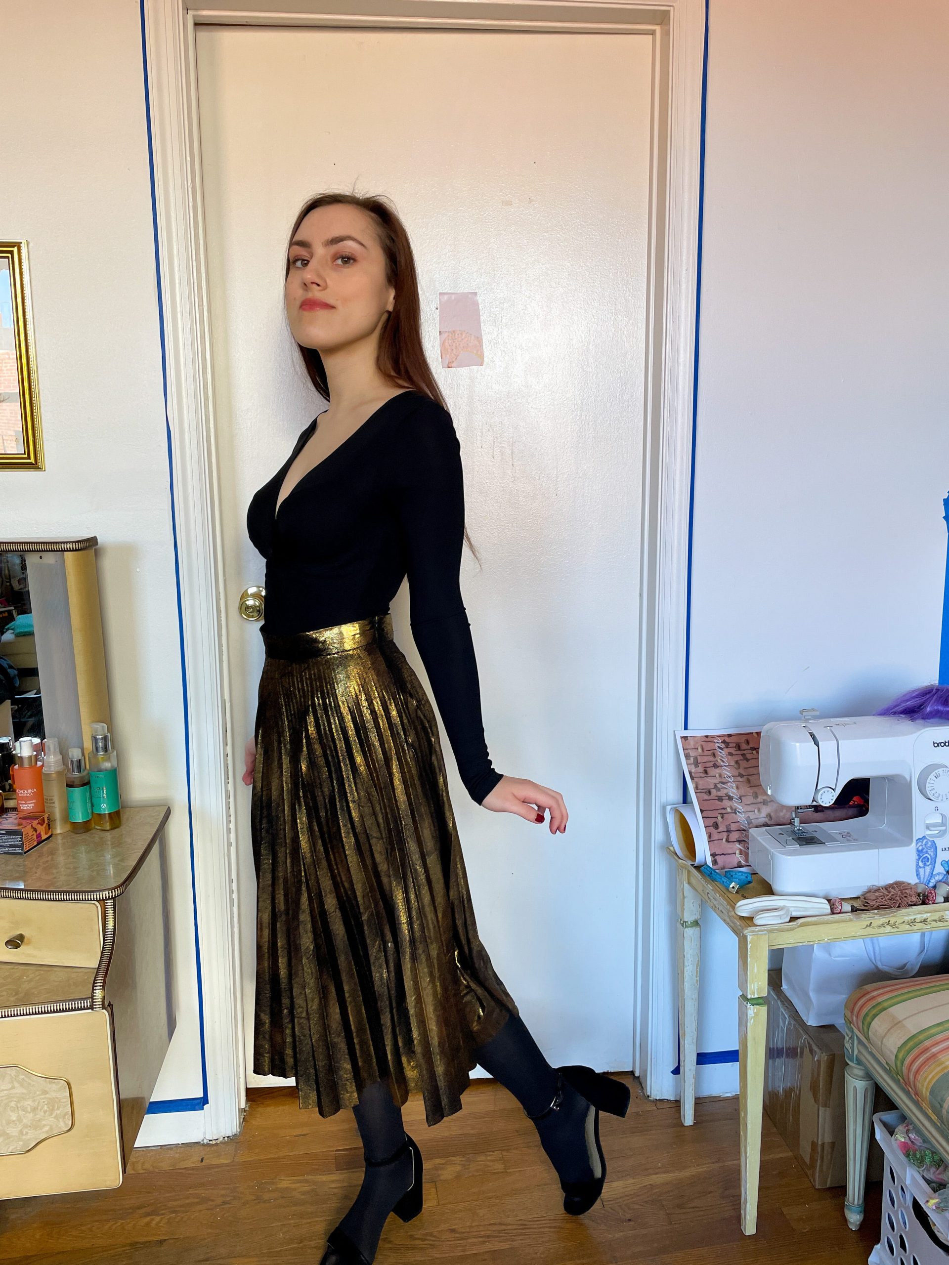 Black wrap top with a gold, knife-pleat skirt and red nail polish
