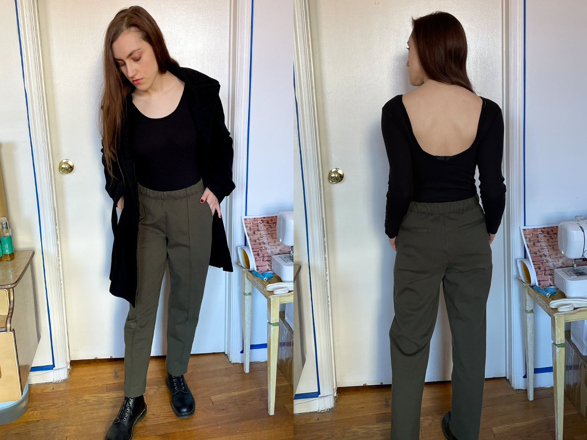 Black scoopneck top, black coat, green pants, black Doc Martens