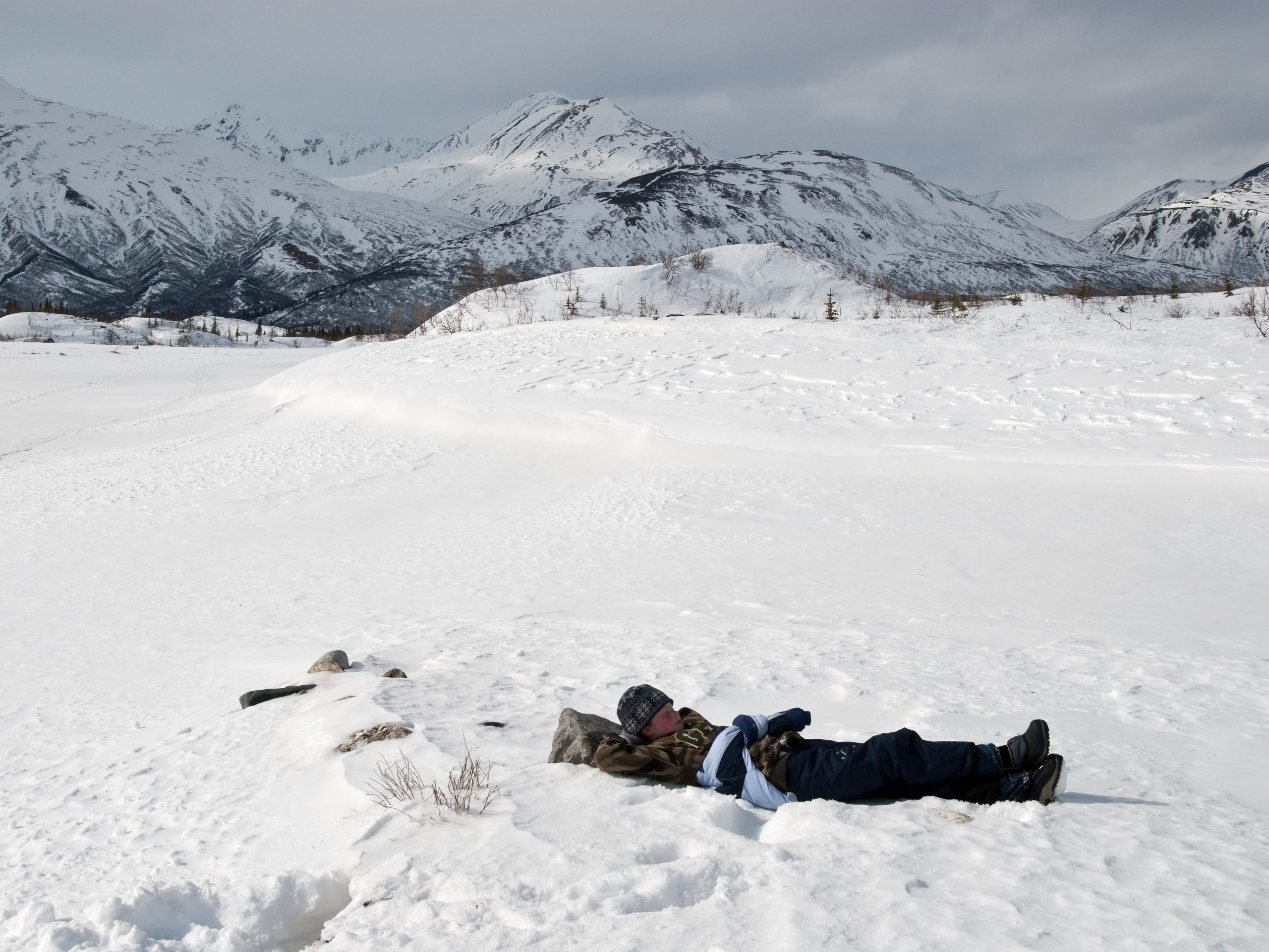 Girl taking break while hiking in snow in Alaska