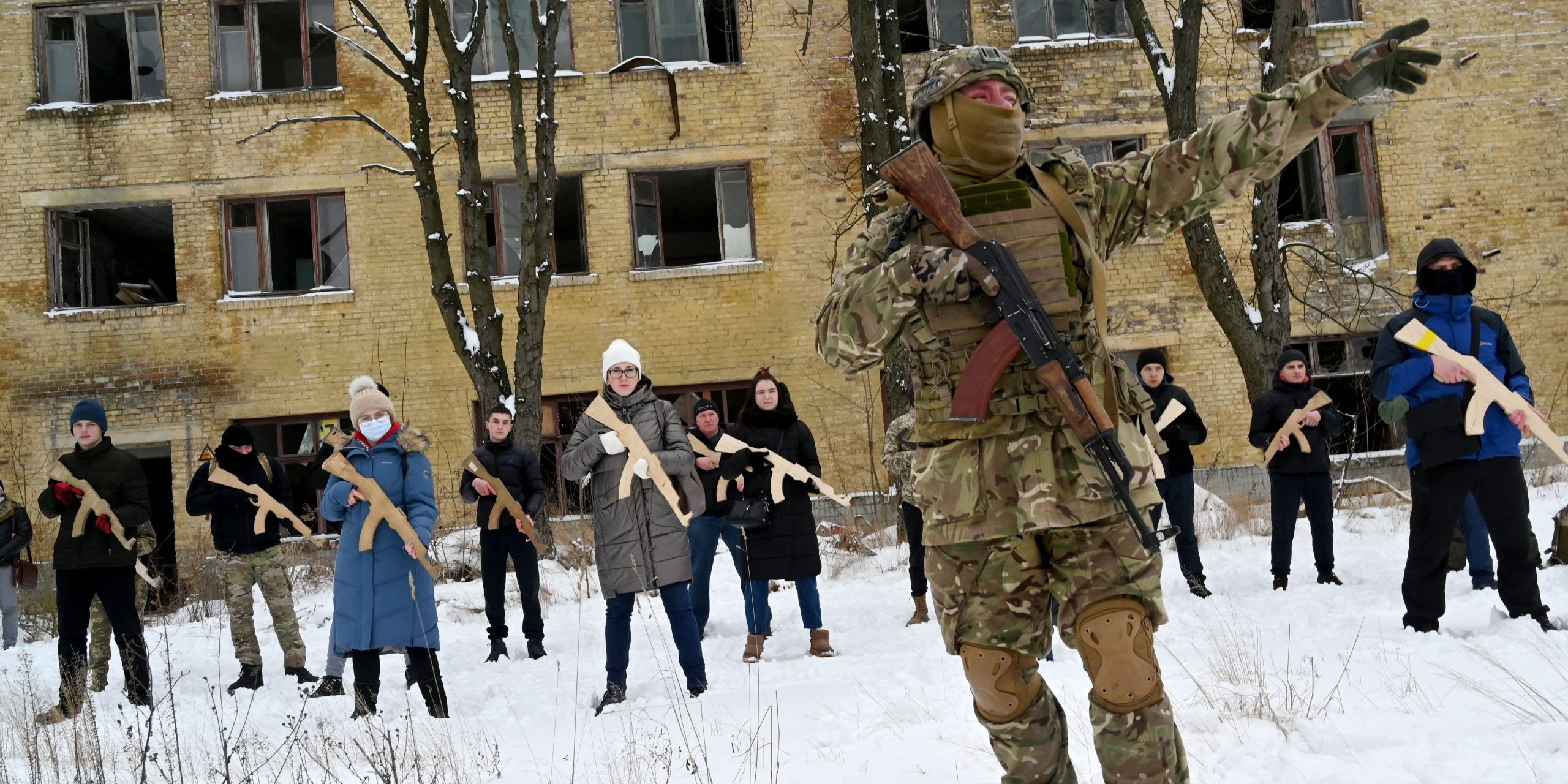 A military instructor teaches civilians holding wooden replicas of Kalashnikov rifles, during a training session at an abandoned factory in the Ukrainian capital of Kyiv on January 30, 2022.